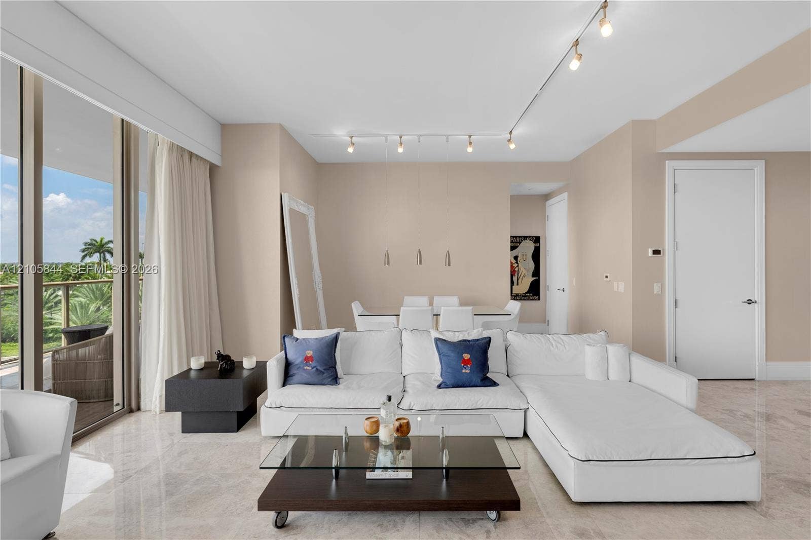 Bal Harbour, Bal Harbour, FL 33154 Interior living space featuring light-toned stone flooring, floor-to-ceiling glass panel doors, and overhead track lighting