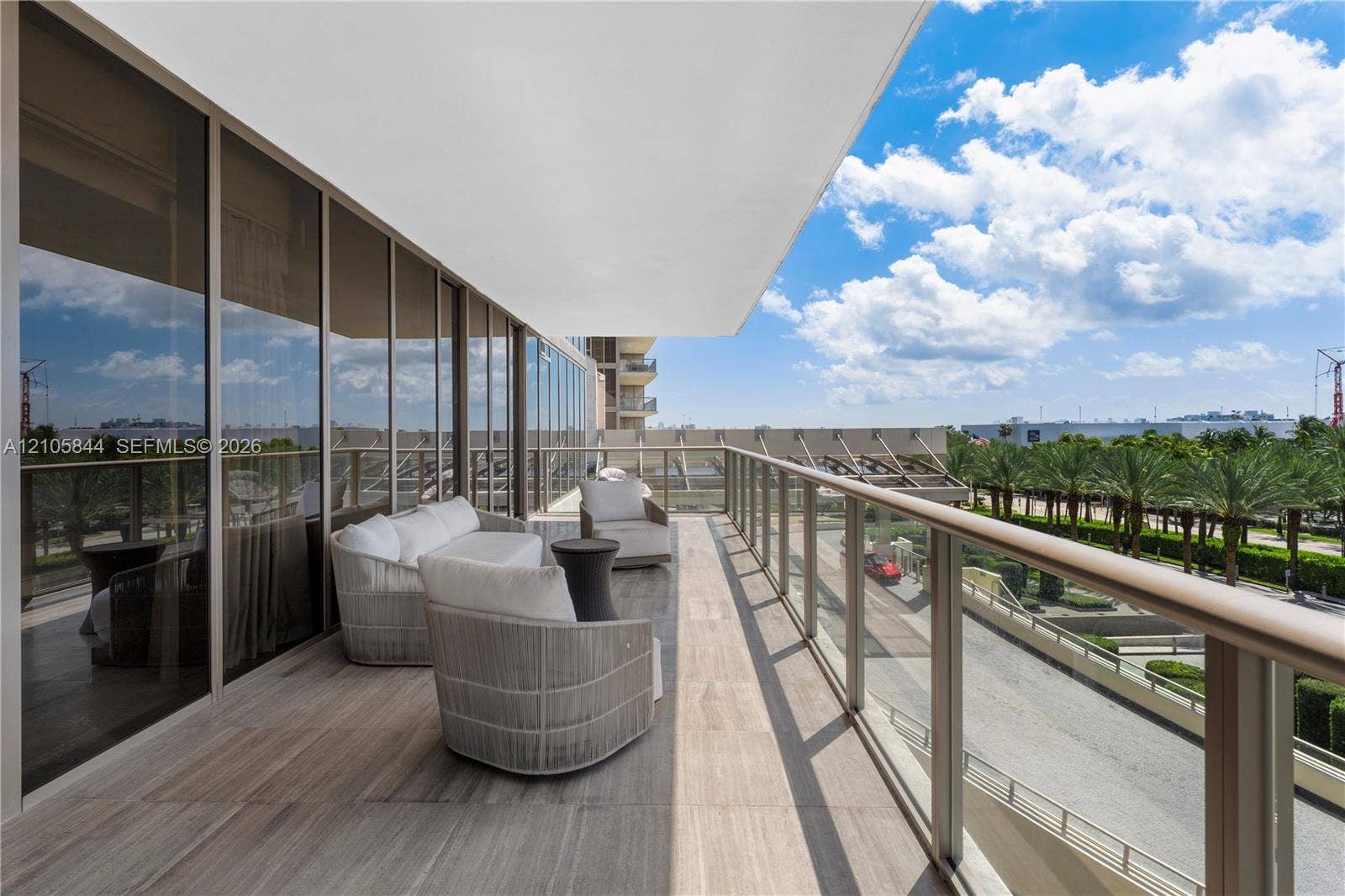 Bal Harbour, Bal Harbour, FL 33154 Expansive covered balcony featuring floor-to-ceiling glass paneling, wood-finish flooring, and a glass-paneled railing with a metal handrail