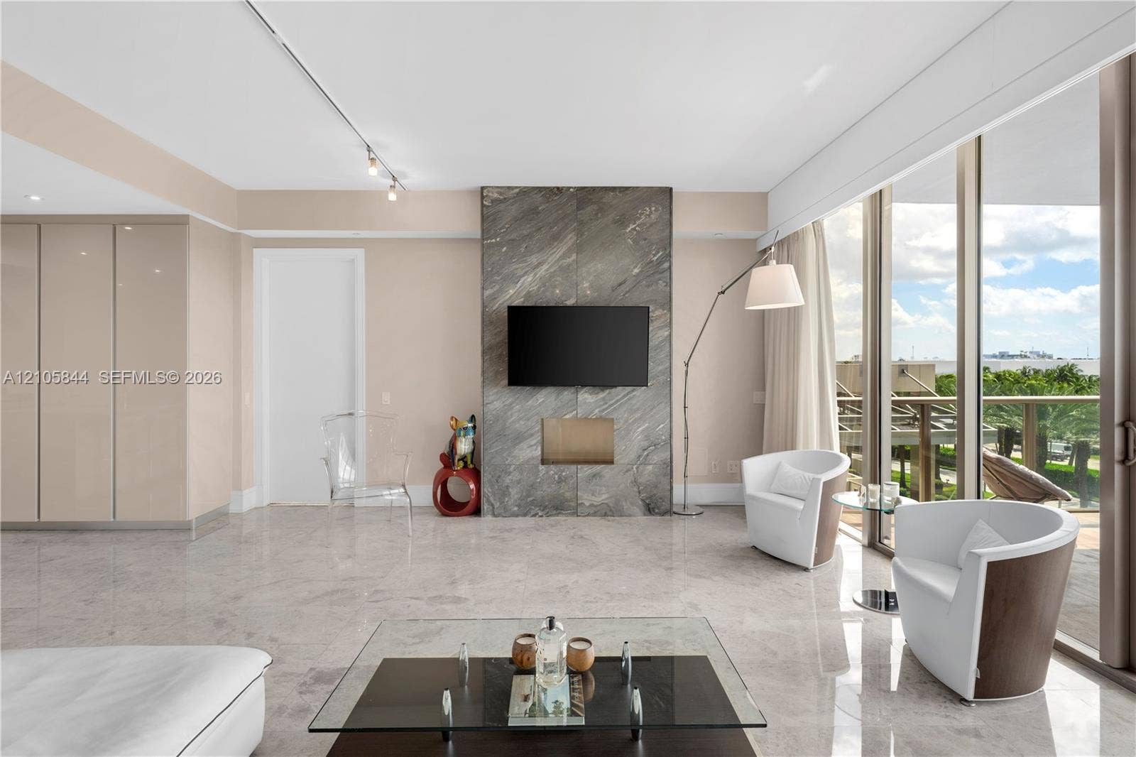 Bal Harbour, Bal Harbour, FL 33154 Full-height stone fireplace surround, floor-to-ceiling glass panel walls, polished stone flooring, and integrated wall cabinetry