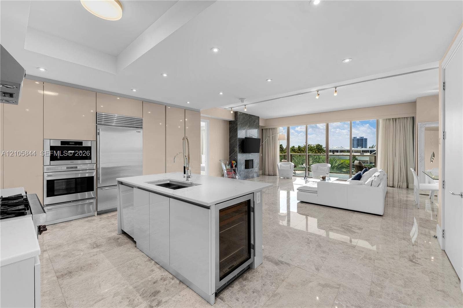 Bal Harbour, Bal Harbour, FL 33154 Kitchen featuring high-gloss cabinetry, stone-finish flooring, a central island with an integrated beverage cooler, stainless steel wall-mounted oven and microwave, and floor-to-ceiling windows