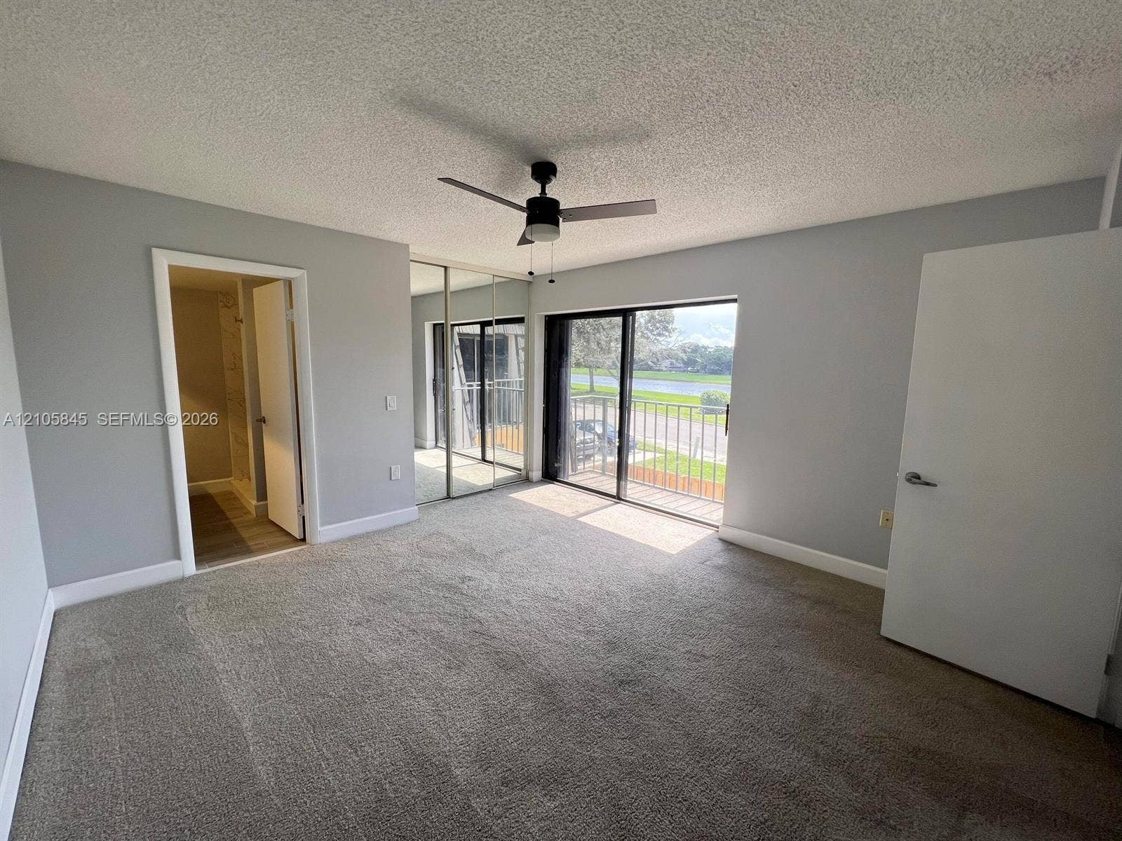 2001 20th Way, #2001, West Palm Beach, West Palm Beach, FL 33407 Neutral-toned interior featuring wall-to-wall carpeting, mirrored closet doors, a ceiling fan with integrated lighting, and a sliding glass door opening to an exterior balcony