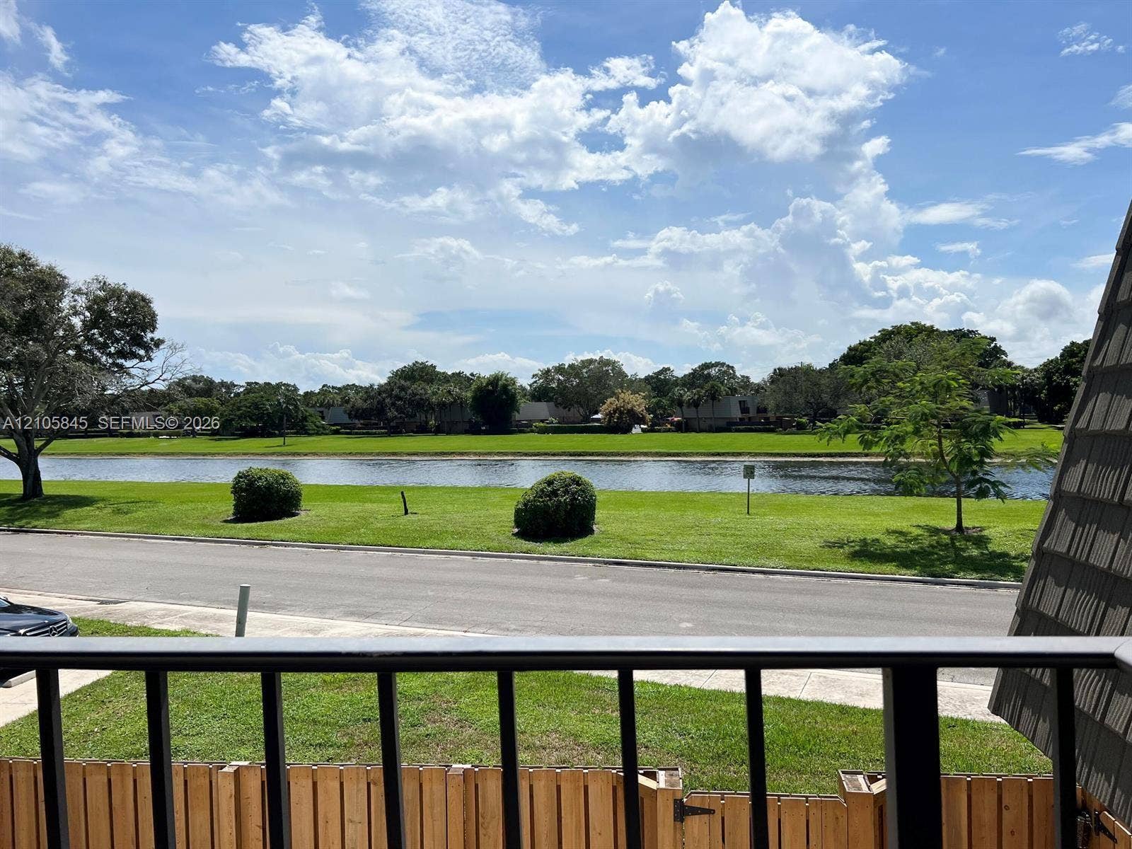 2001 20th Way, #2001, West Palm Beach, West Palm Beach, FL 33407 Outdoor balcony featuring a metal railing, overlooking a water feature, manicured landscaping, and asphalt paving
