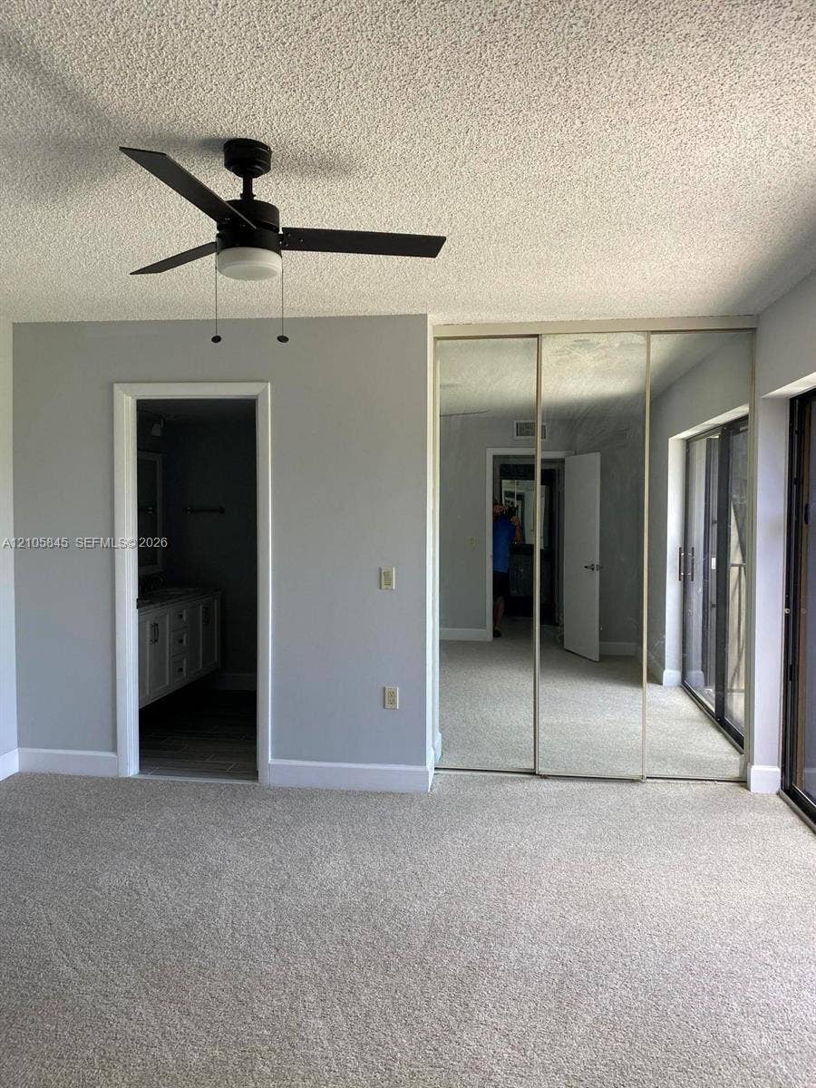 2001 20th Way, #2001, West Palm Beach, West Palm Beach, FL 33407 Neutral-toned interior featuring wall-to-wall carpeting, three-panel mirrored closet doors, a ceiling fan with integrated lighting, and a sliding glass door