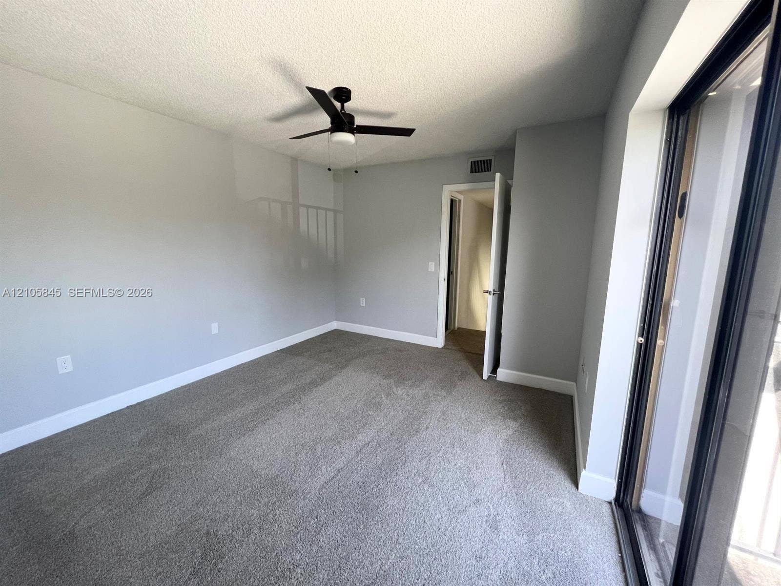 2001 20th Way, #2001, West Palm Beach, West Palm Beach, FL 33407 Interior space featuring neutral wall tones, wall-to-wall carpeting, a black ceiling fan with integrated lighting, and a sliding glass door