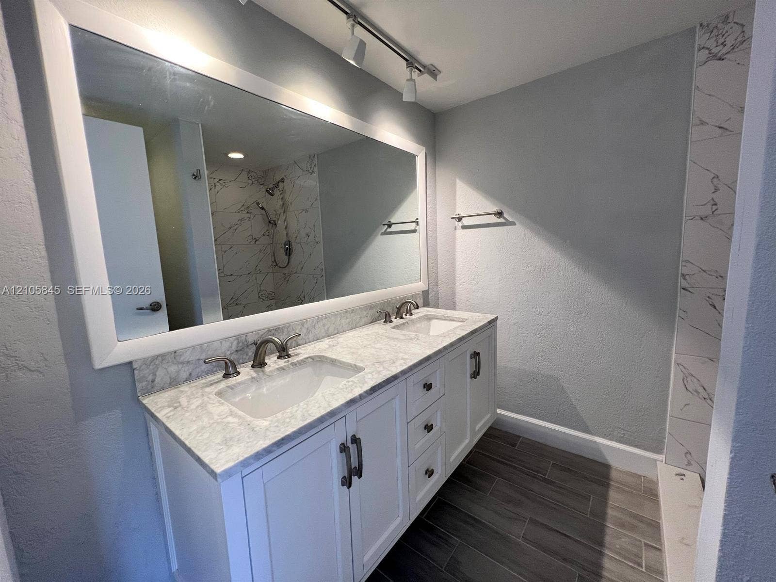 2001 20th Way, #2001, West Palm Beach, West Palm Beach, FL 33407 Double vanity with white cabinetry, stone-surface countertop, dual undermount sinks, wide-frame mirror, and wood-finish flooring