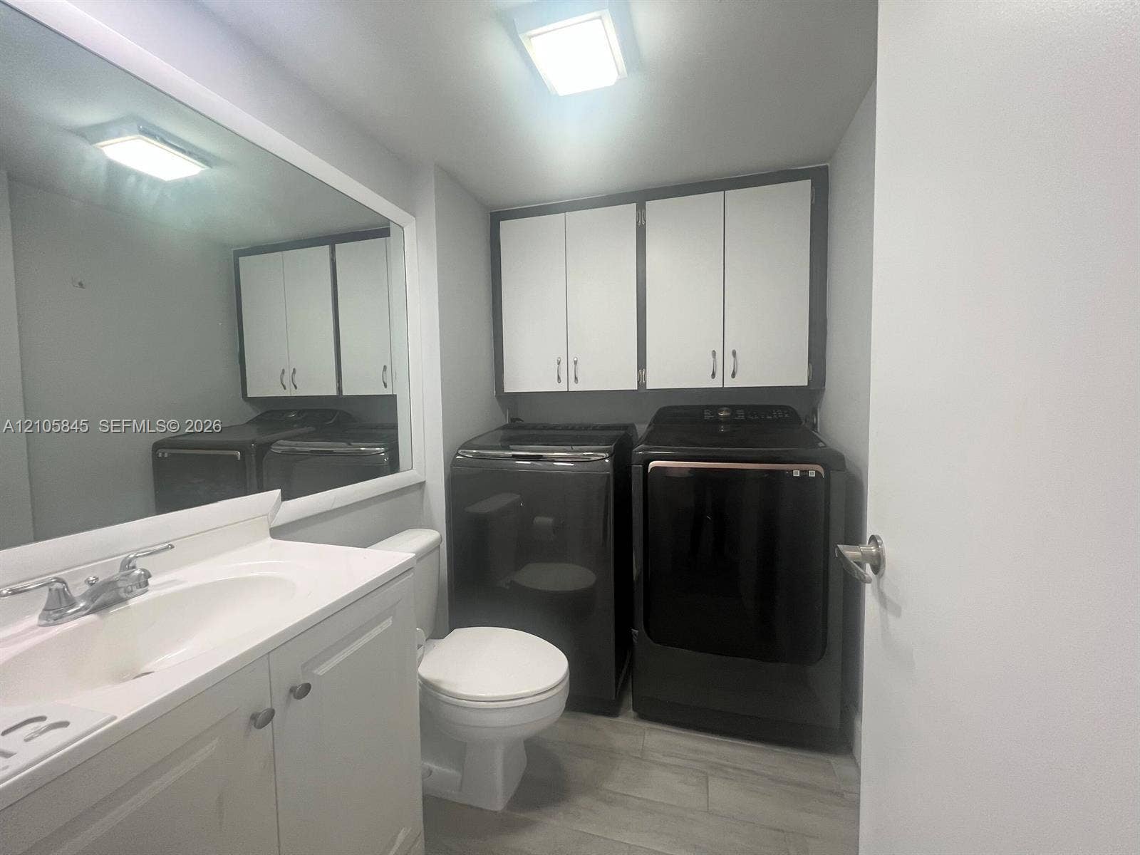 2001 20th Way, #2001, West Palm Beach, West Palm Beach, FL 33407 Bathroom featuring white cabinetry, integrated sink, large wall-mounted mirror, overhead lighting, and wood-finish tile flooring