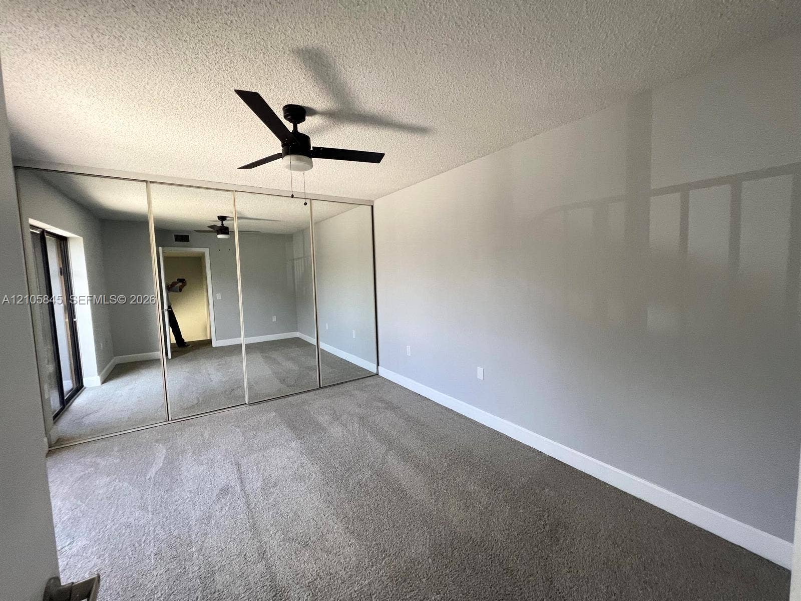 2001 20th Way, #2001, West Palm Beach, West Palm Beach, FL 33407 Room featuring wall-to-wall mirrored sliding closet doors, neutral carpeting, and a ceiling fan with integrated lighting