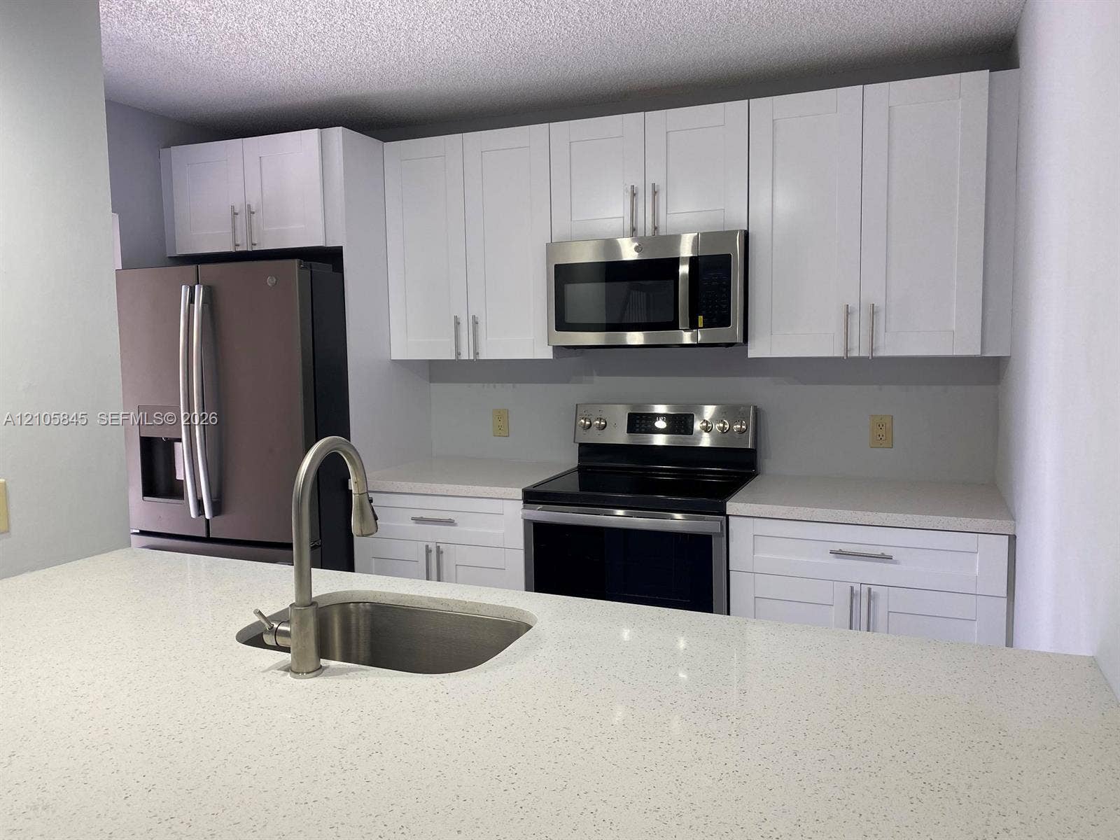 2001 20th Way, #2001, West Palm Beach, West Palm Beach, FL 33407 Kitchen featuring white shaker-style cabinetry, solid-surface countertops, stainless steel appliances, and an undermount sink with a high-arch pull-down faucet