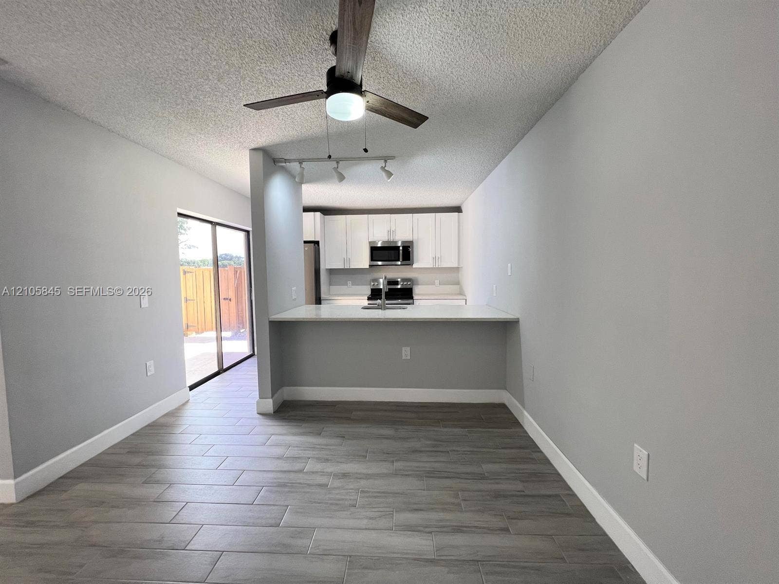 2001 20th Way, #2001, West Palm Beach, West Palm Beach, FL 33407 Kitchen featuring white cabinetry, stainless steel appliances, a peninsula counter with a sink, wood-finish tile flooring, and a ceiling fan with integrated lighting