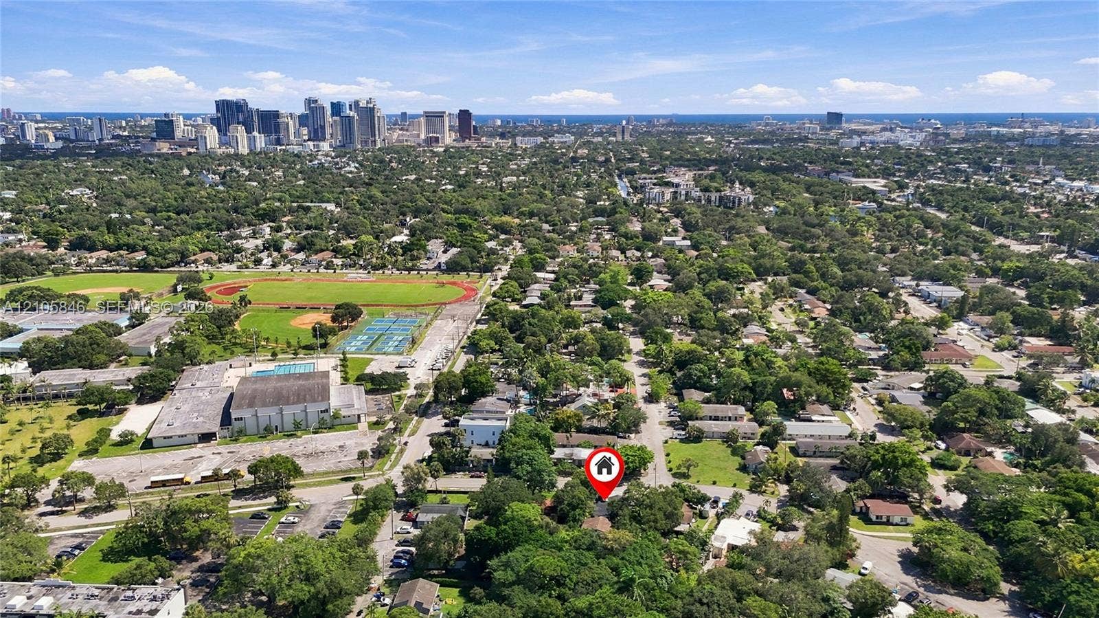 Aerial perspective showcasing an urban setting with proximity to metropolitan skylines and nearby athletic fields