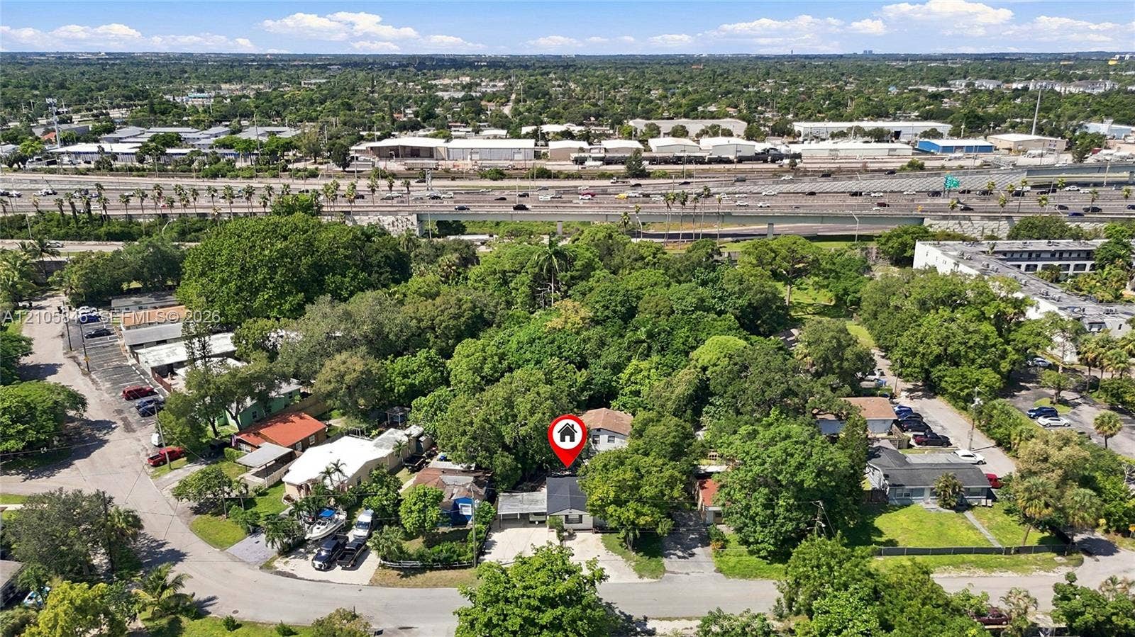Aerial perspective featuring a single-story residence situated on a lot with mature tree canopy and paved driveway