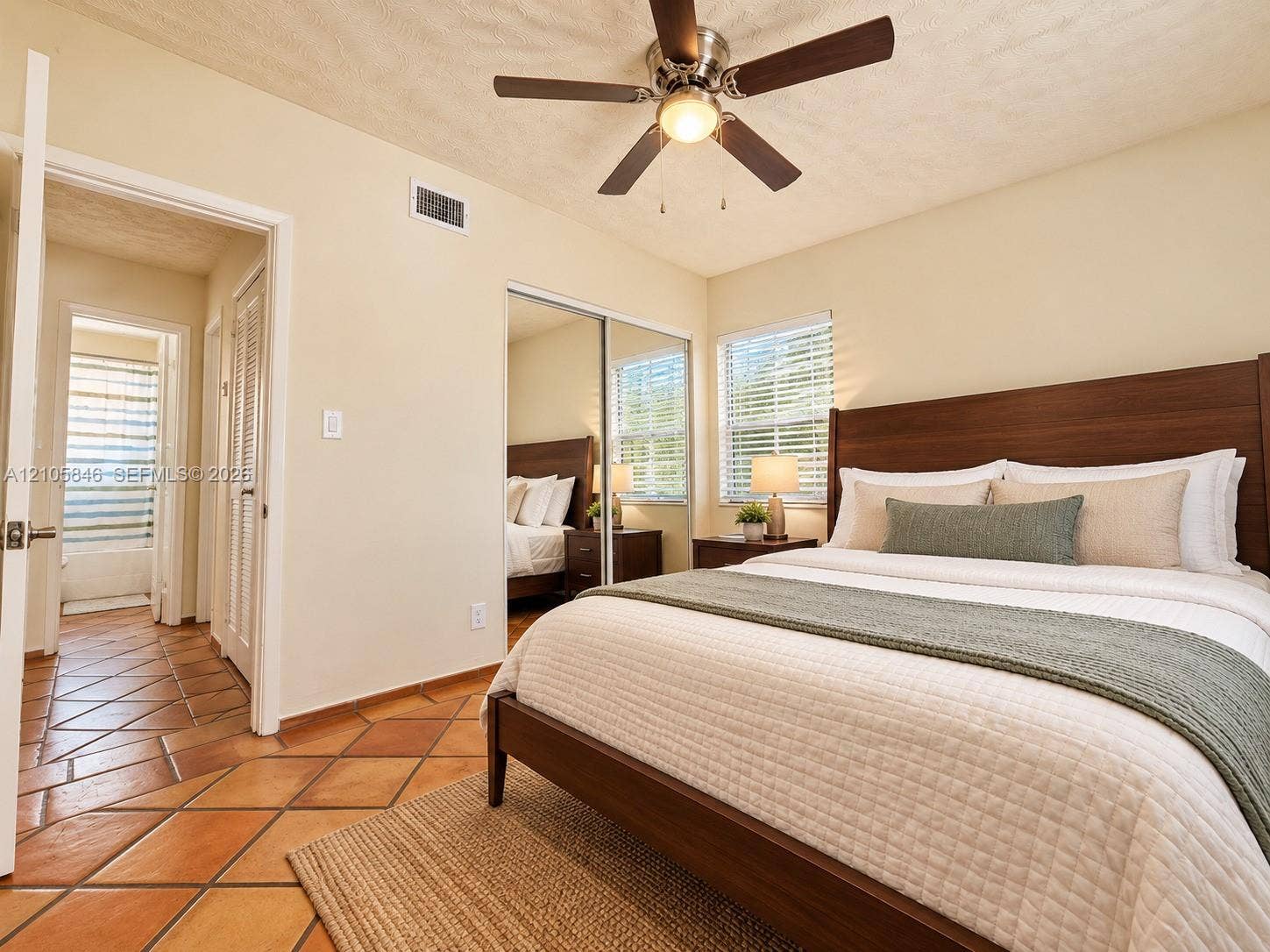 Ceramic tile flooring, ceiling fan with integrated light fixture, and floor-to-ceiling mirrored closet doors