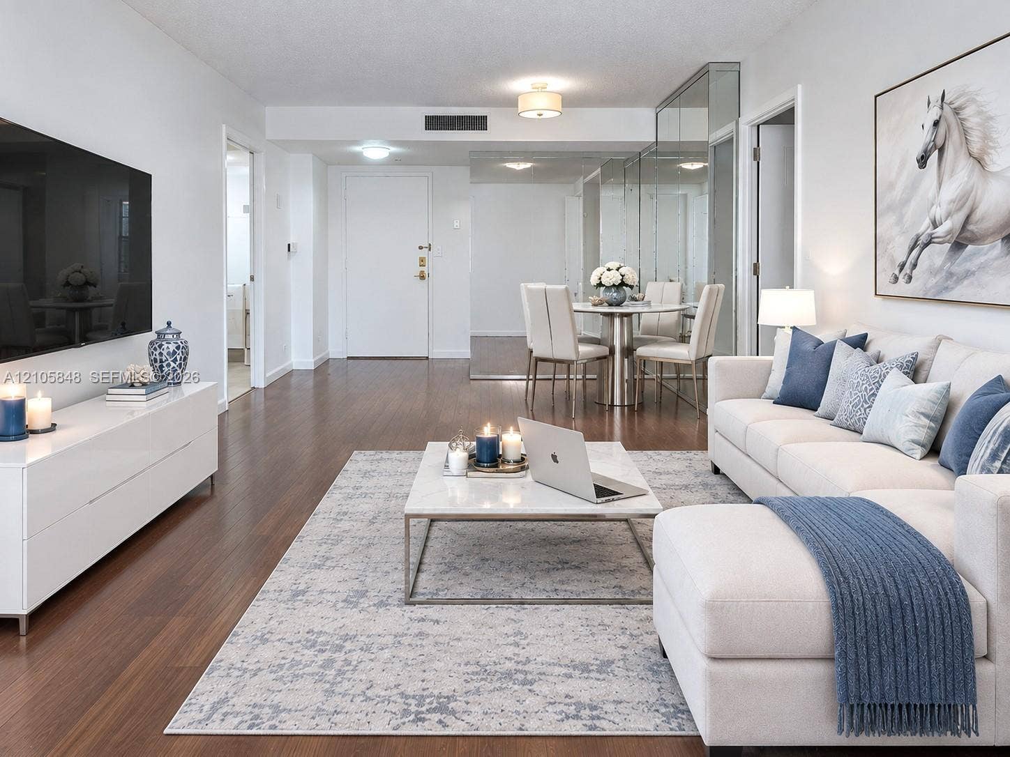 Open-concept living space featuring wood-finish flooring, mirrored wall paneling, and flush-mount ceiling lighting