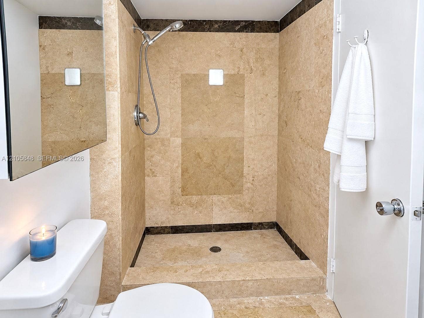 Walk-in shower featuring floor-to-ceiling stone tile surrounds, stone accent tiling, and a hand-held shower fixture