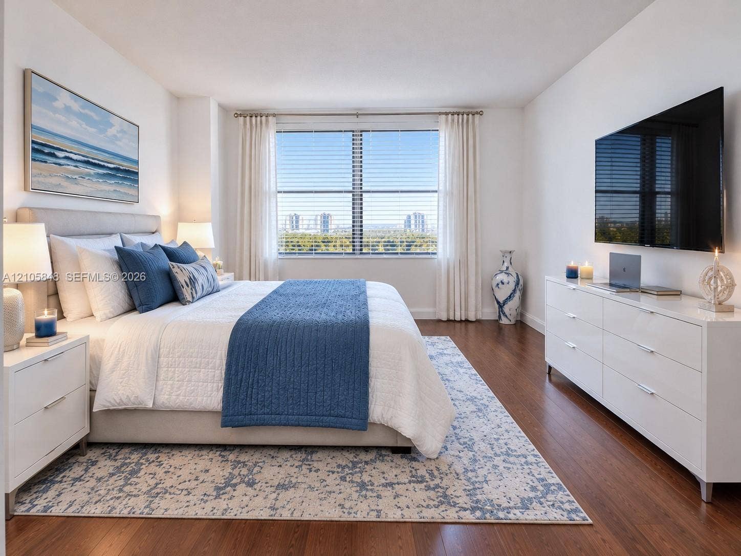 Spacious interior featuring wood-finish flooring, a large window with blind treatments, and neutral wall tones