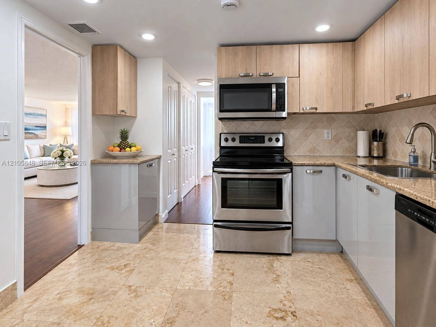 Kitchen featuring light wood-finish upper cabinetry, grey lower cabinetry, stone-finish countertops, stainless steel appliances, and large-format tile flooring