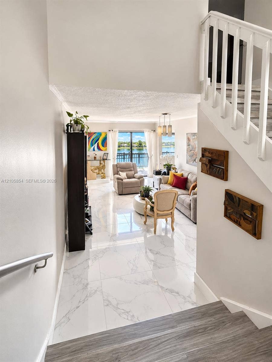 454 NW 97th Place, Miami, FL 33172 Large-format tile flooring with polished finish, staircase with wood-finish treads and white balusters, metal handrail, and floor-to-ceiling glass sliding doors