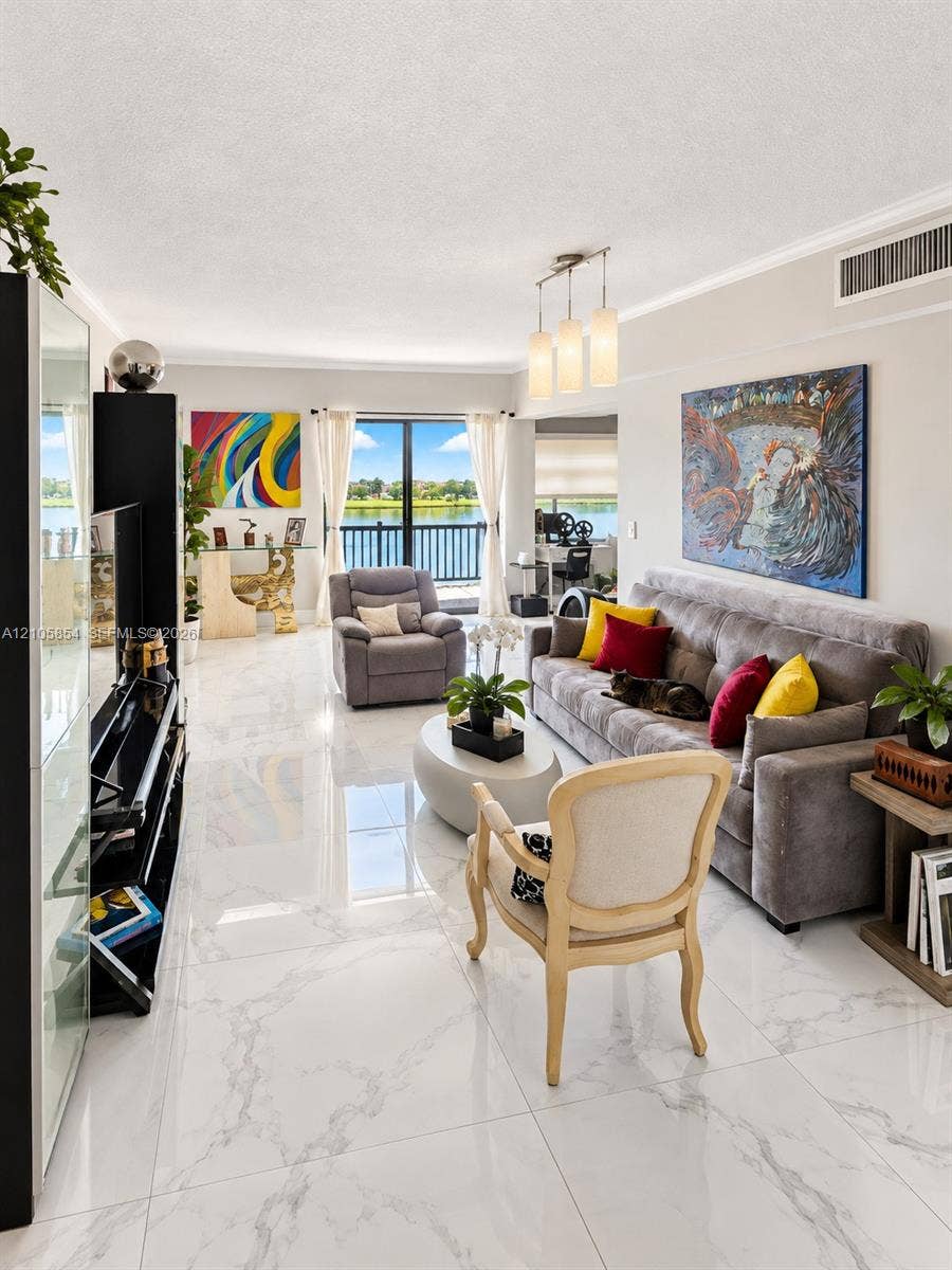 454 NW 97th Place, Miami, FL 33172 Living area featuring polished stone-finish tile flooring, a multi-light pendant fixture, and glass sliding doors providing exterior access