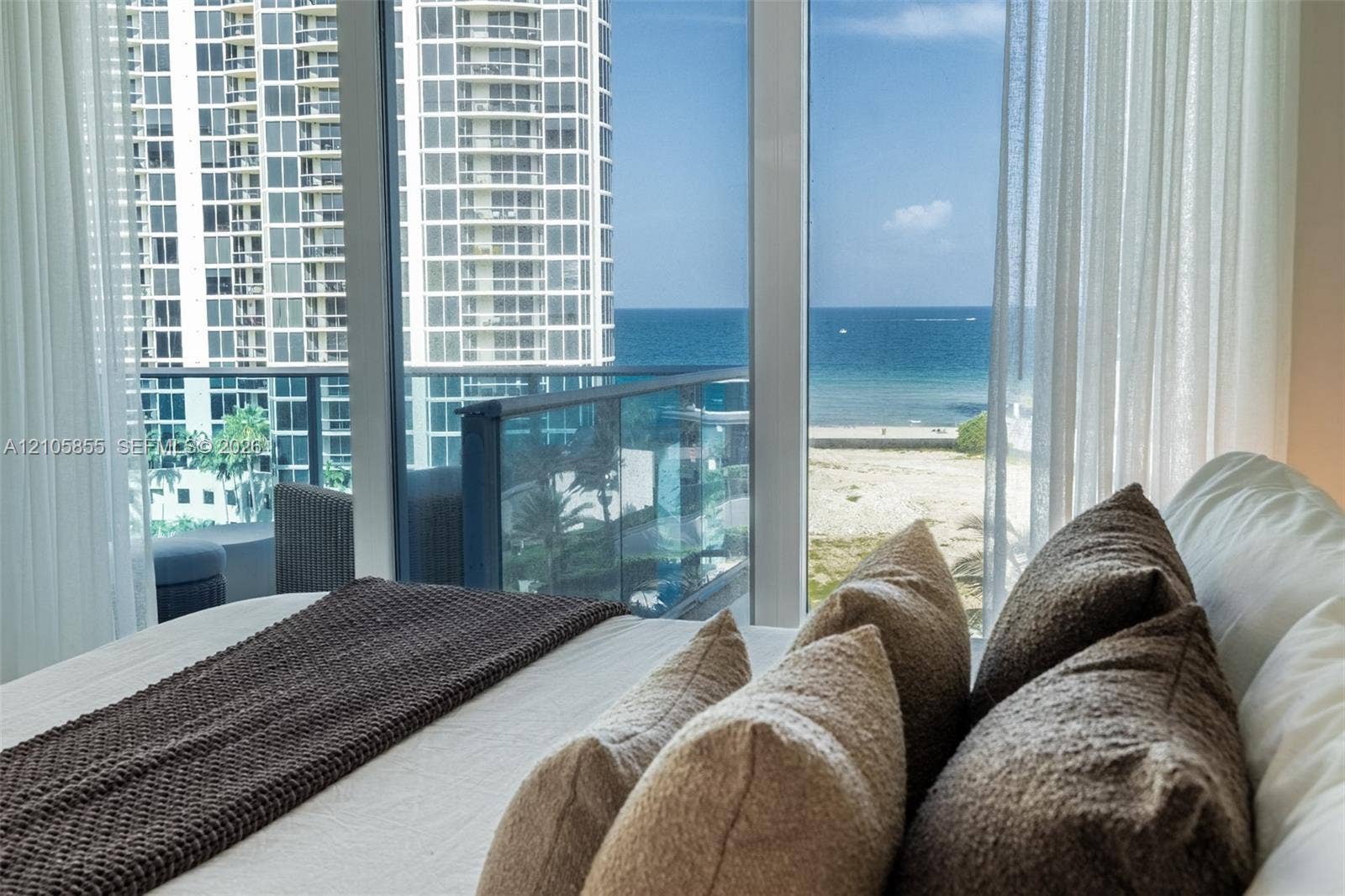 17550 Collins Avenue, #703, Sunny Isles Beach, Sunny Isles Beach, FL 33160 Floor-to-ceiling glass windows, balcony with blue-tinted glass railing, and ocean and coastal exposure