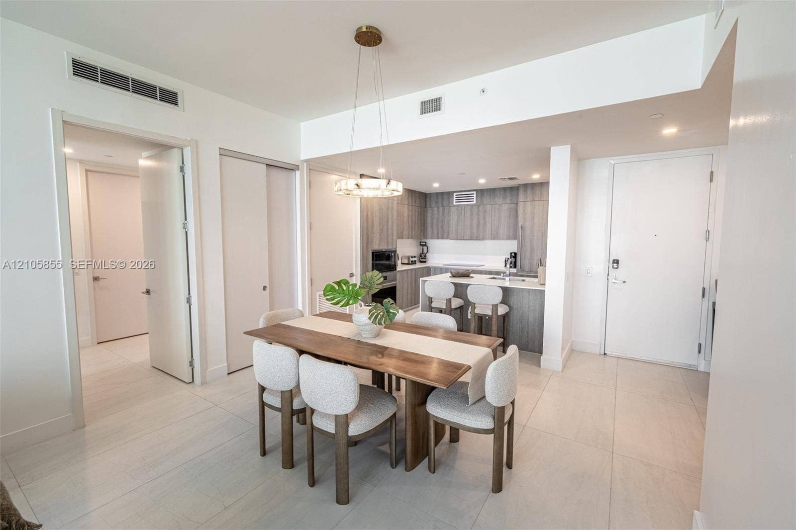 17550 Collins Avenue, #703, Sunny Isles Beach, Sunny Isles Beach, FL 33160 Kitchen featuring flat-panel cabinetry, light-toned countertops, a breakfast bar, and stainless steel appliances, highlighted by a contemporary circular pendant light fixture and consistent tile flooring