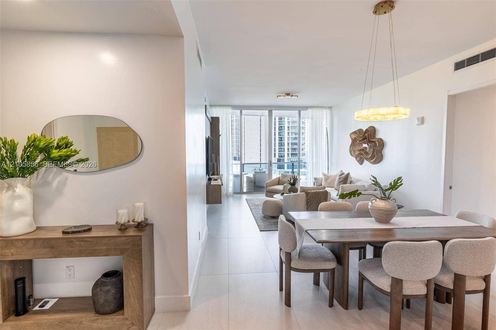 17550 Collins Avenue, #703, Sunny Isles Beach, Sunny Isles Beach, FL 33160 Large-format tile flooring, circular pendant lighting, and floor-to-ceiling glass doors opening to a balcony