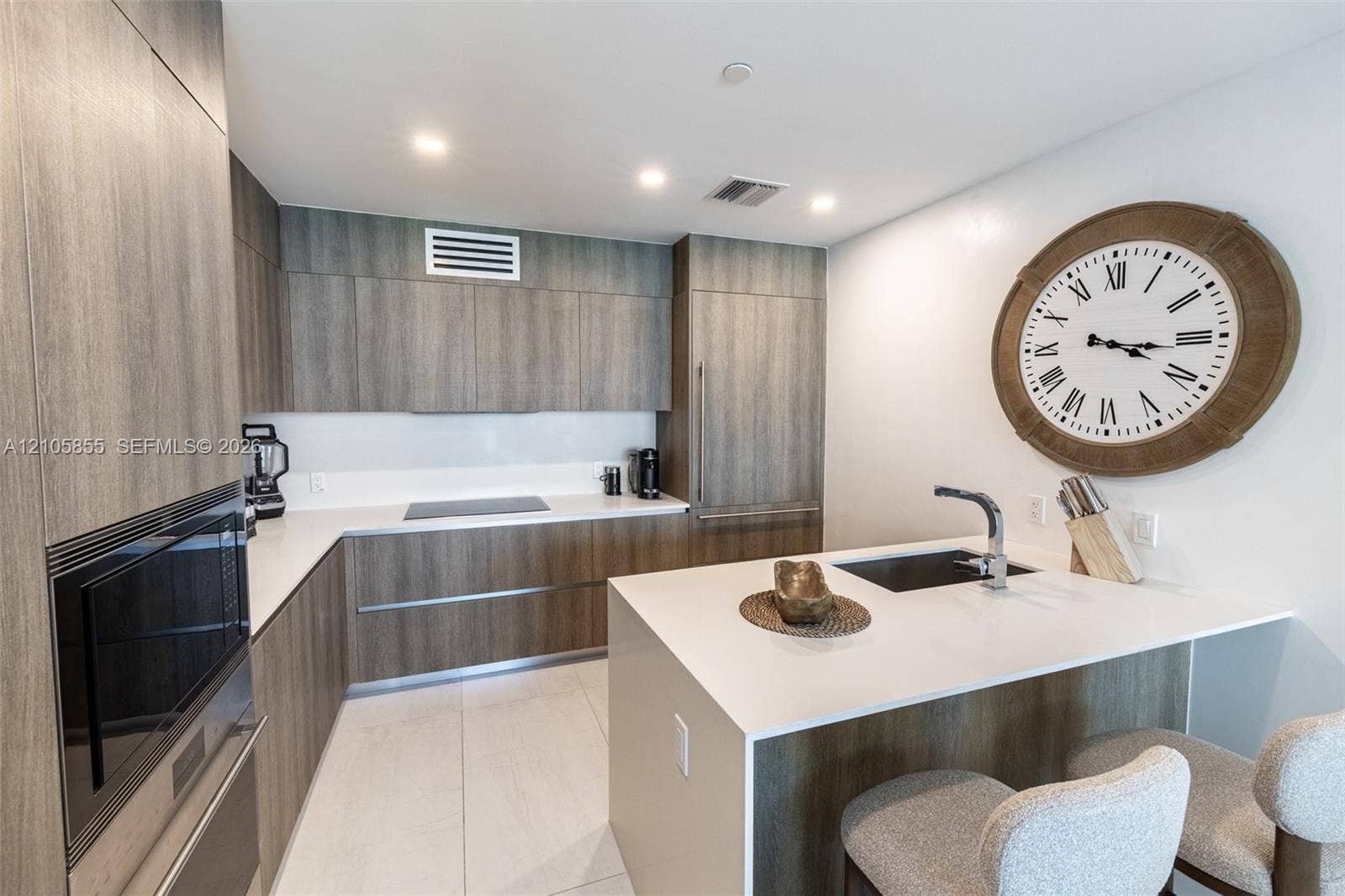 17550 Collins Avenue, #703, Sunny Isles Beach, Sunny Isles Beach, FL 33160 Kitchen featuring flat-panel wood-finish cabinetry, white countertops, a central island with a built-in sink, recessed lighting, and integrated stainless steel appliances