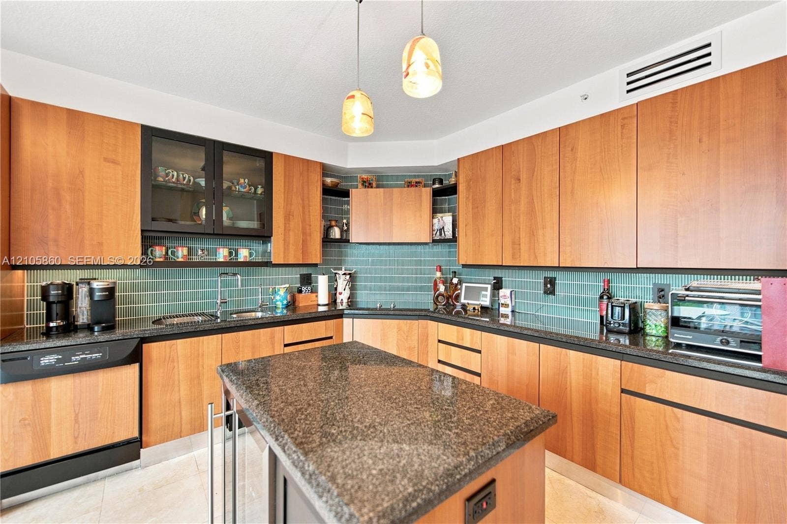 17555 Collins Avenue, #1903, Sunny Isles Beach, FL 33160 Kitchen featuring custom wood cabinetry, dark stone countertops, a central island, blue subway tile backsplash, and dual pendant lighting