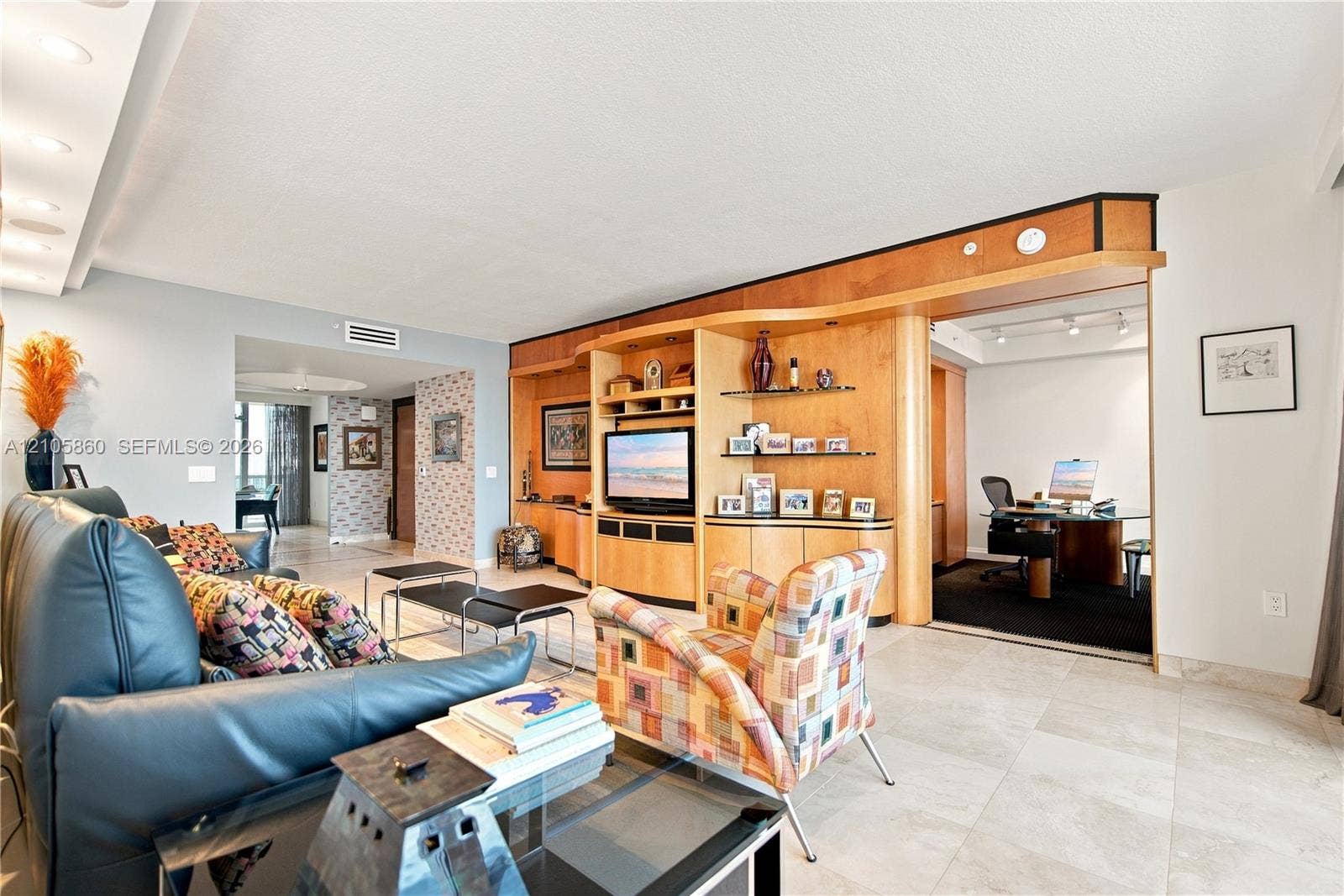 17555 Collins Avenue, #1903, Sunny Isles Beach, FL 33160 Living area featuring custom light-finish wood cabinetry with integrated shelving and recessed lighting, neutral stone-finish flooring, and recessed ceiling lighting