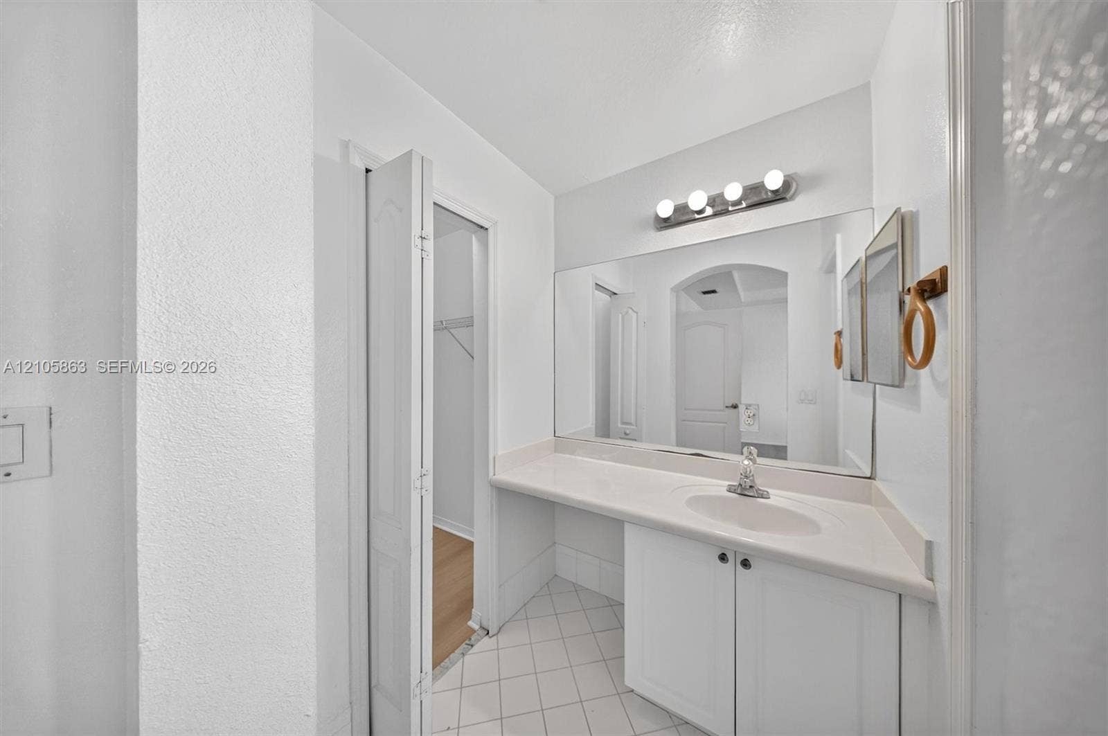 8846 W Flagler Street, #5, Miami, FL 33174 Bathroom featuring a vanity with a solid-surface countertop, an integrated oval sink, a large wall-mounted mirror, and tile flooring laid on a diagonal