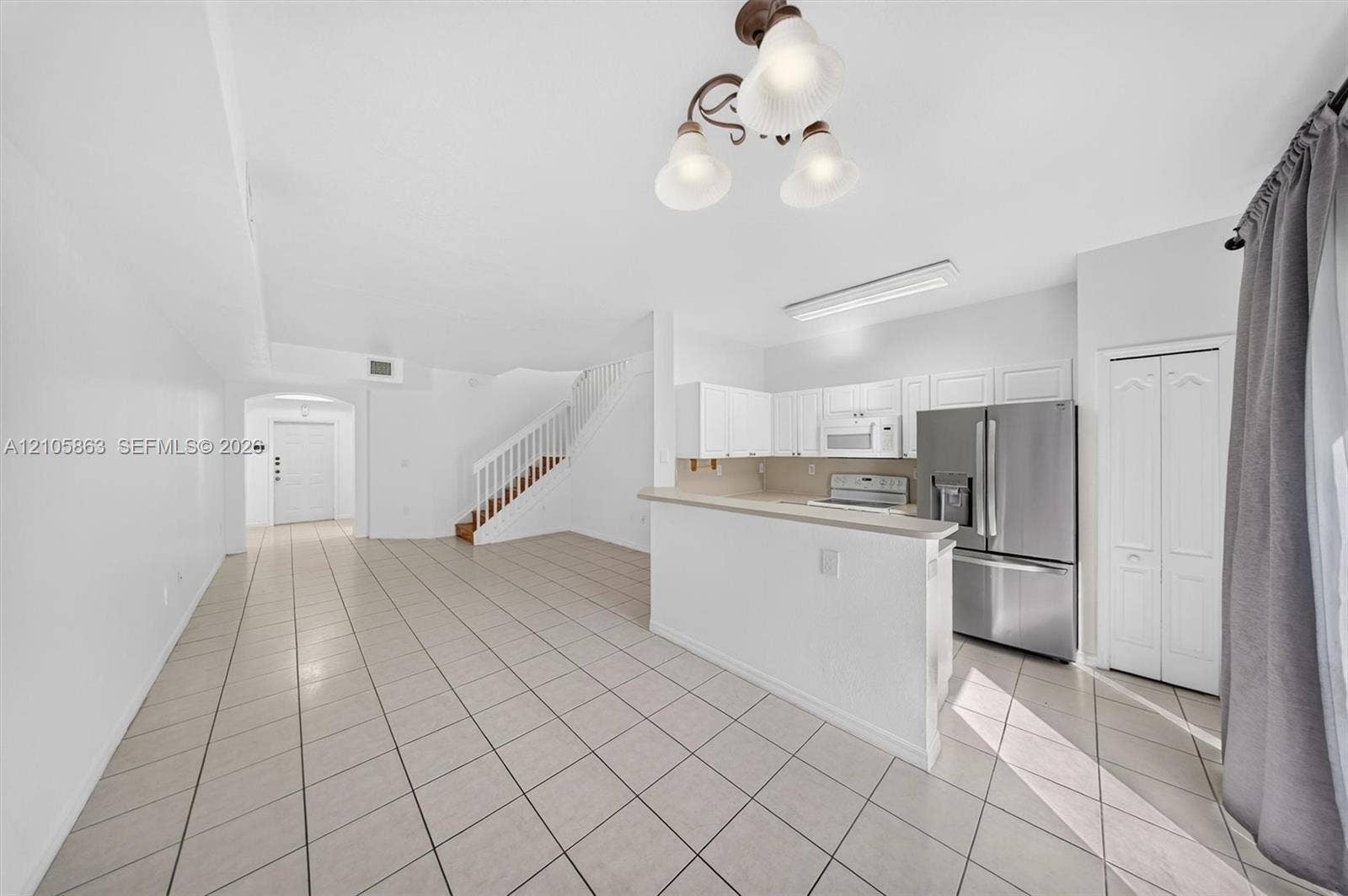 8846 W Flagler Street, #5, Miami, FL 33174 Kitchen featuring stainless steel appliances, white cabinetry, a breakfast bar, ceramic tile flooring, and a multi-light chandelier