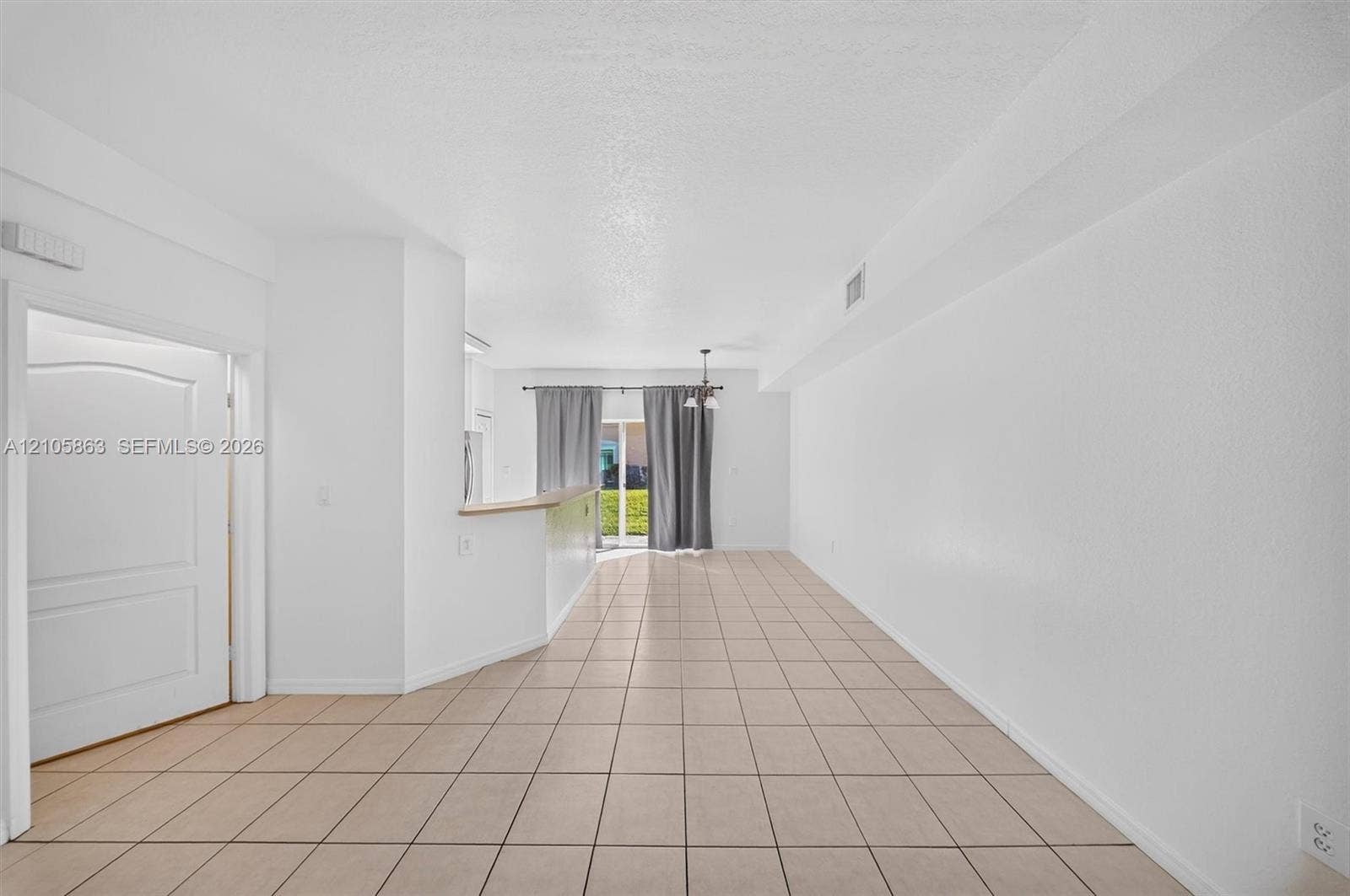 8846 W Flagler Street, #5, Miami, FL 33174 Neutral ceramic tile flooring, kitchen peninsula with a light-toned countertop, and sliding glass doors