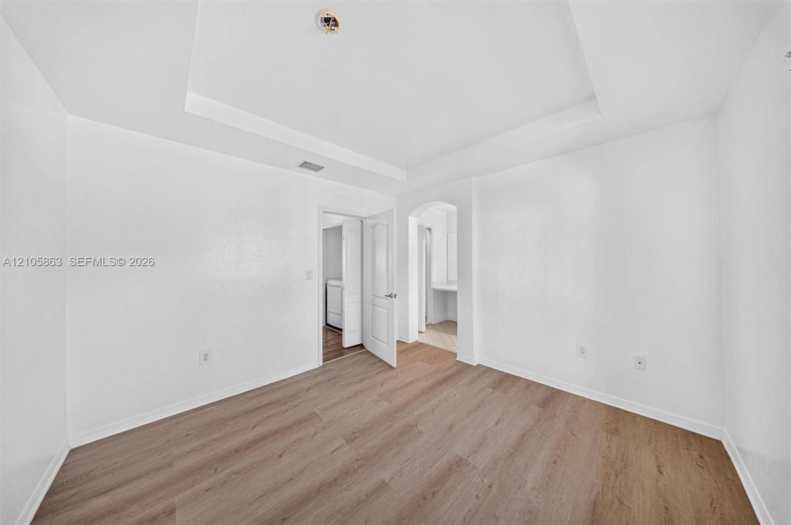 8846 W Flagler Street, #5, Miami, FL 33174 Interior space featuring a recessed tray ceiling, wood-finish flooring, and an arched entry