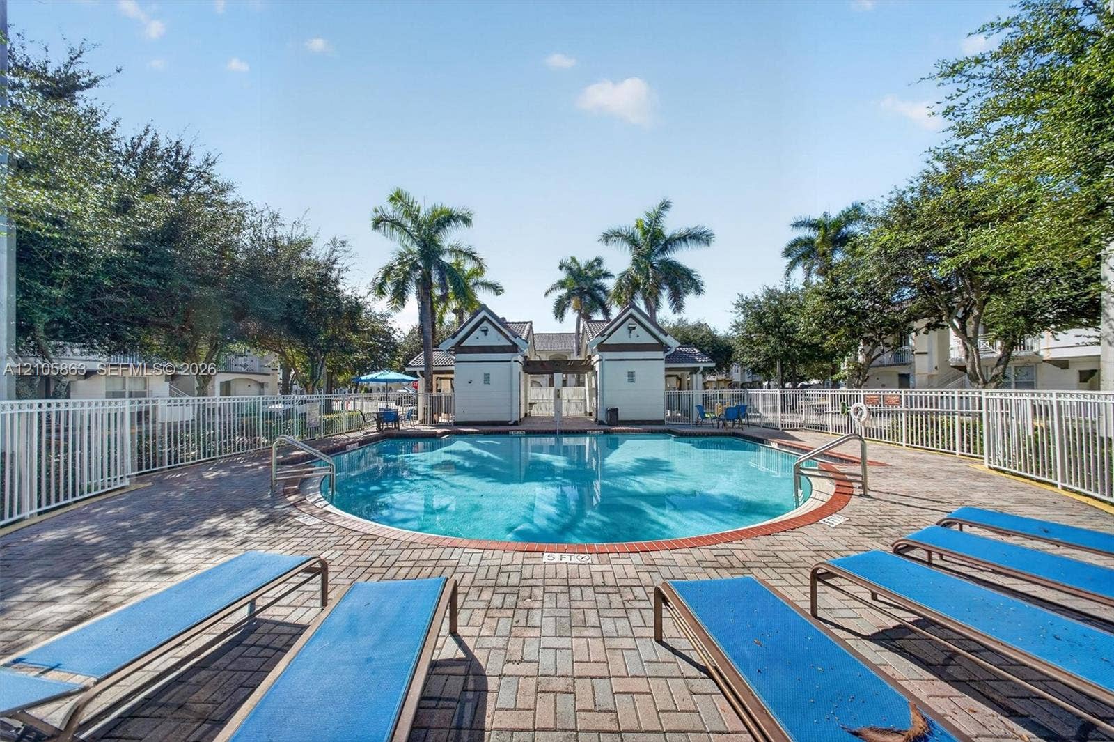 8846 W Flagler Street, #5, Miami, FL 33174 Swimming pool with circular basin, paver patio, white perimeter fencing, and dual cabana structures