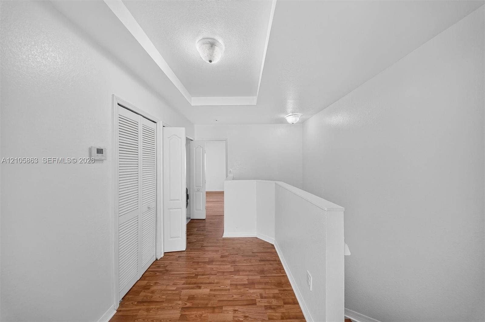 8846 W Flagler Street, #5, Miami, FL 33174 Tray ceiling with flush-mount lighting, wood-finish flooring, and white louvered-door closet