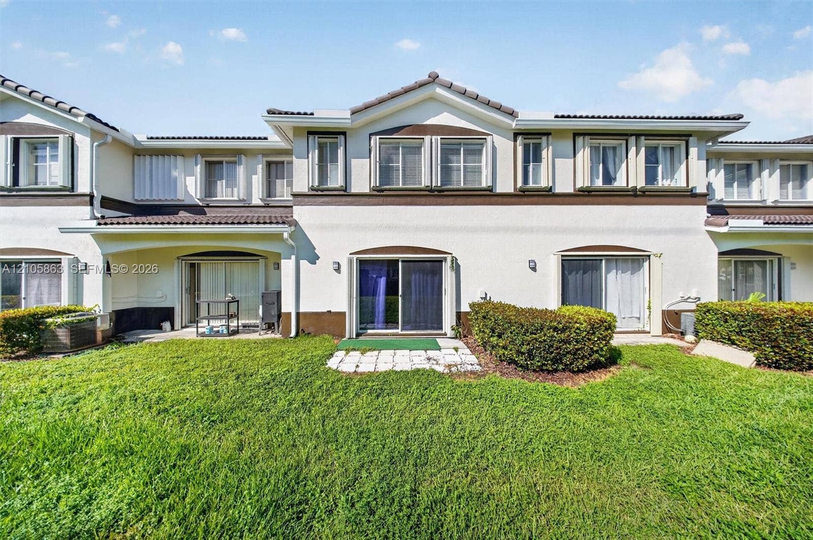 8846 W Flagler Street, #5, Miami, FL 33174 Stucco exterior featuring dual-tone trim, multi-pane windows, a tiled roofline, and sliding glass door access to a private lawn