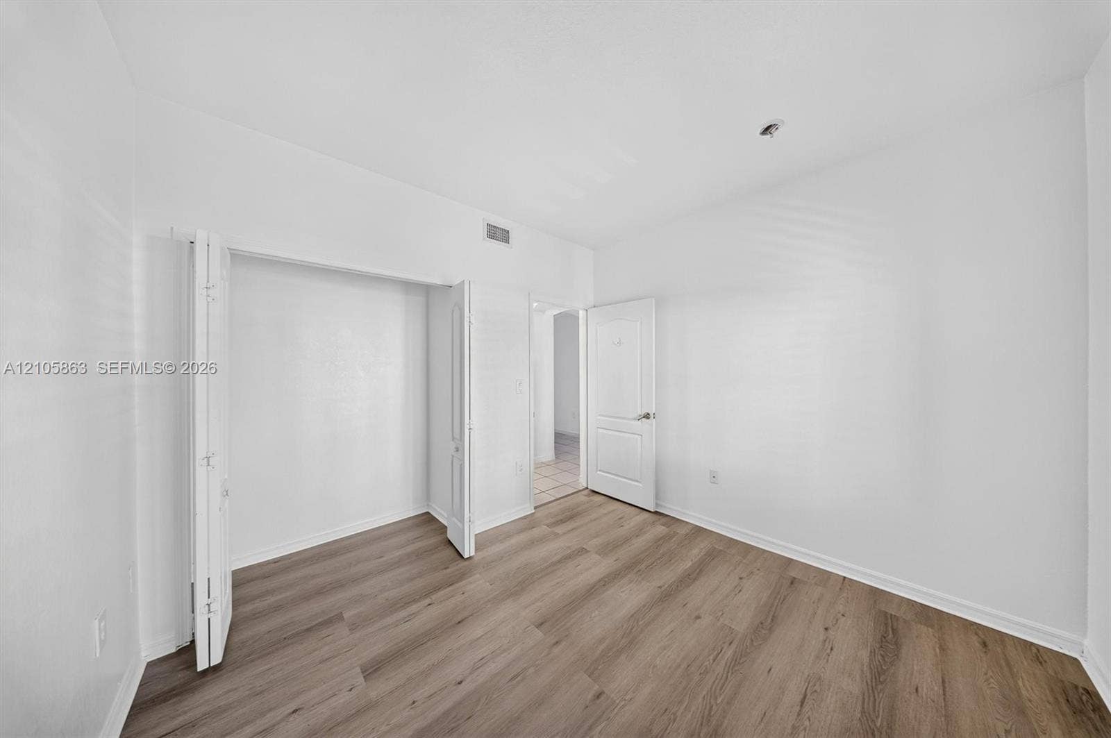 8846 W Flagler Street, #5, Miami, FL 33174 Room featuring wood-finish flooring, a multi-panel door, and a built-in closet with bi-fold doors