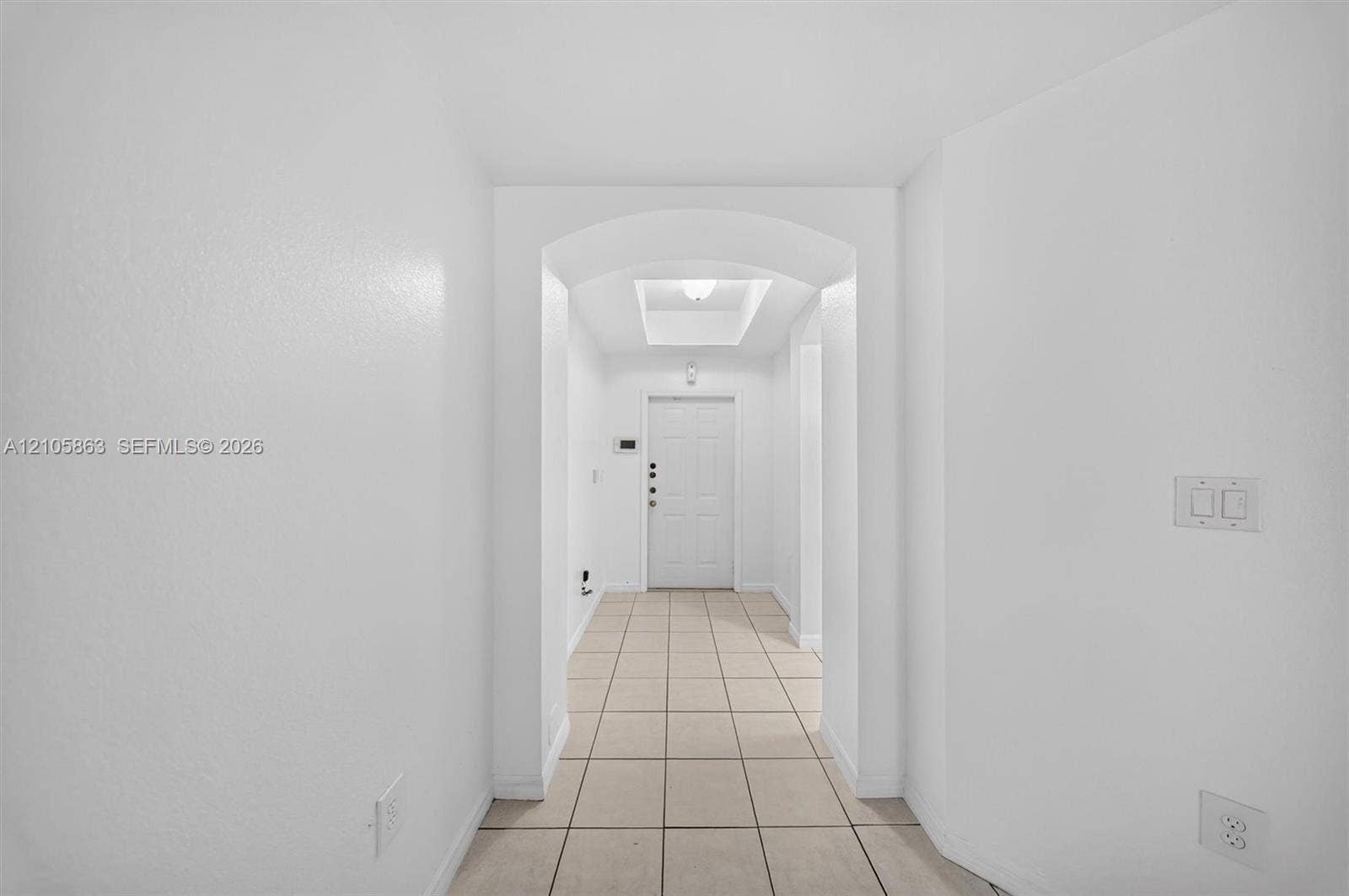 8846 W Flagler Street, #5, Miami, FL 33174 Entryway featuring tile flooring, an arched threshold, a recessed ceiling tray, and a paneled entry door