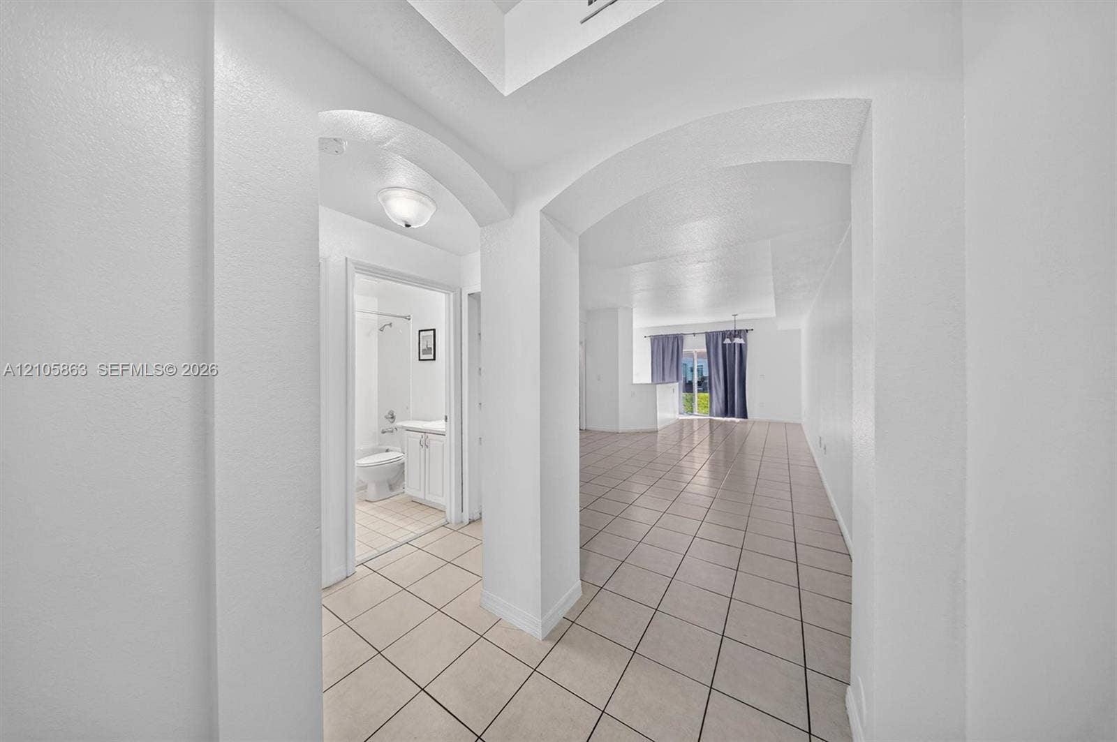 8846 W Flagler Street, #5, Miami, FL 33174 Interior featuring ceramic tile flooring, arched doorways, recessed ceiling detail, and neutral wall tones