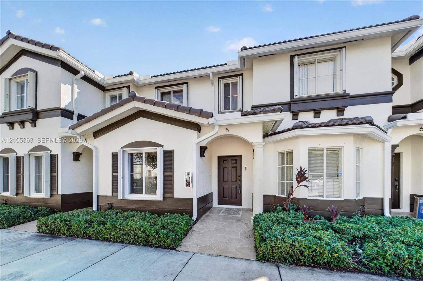 8846 W Flagler Street, #5, Miami, FL 33174 Two-story exterior featuring a light-toned stucco finish, dark wood-tone trim, a tiled roof, multi-pane windows, and a paved stone walkway