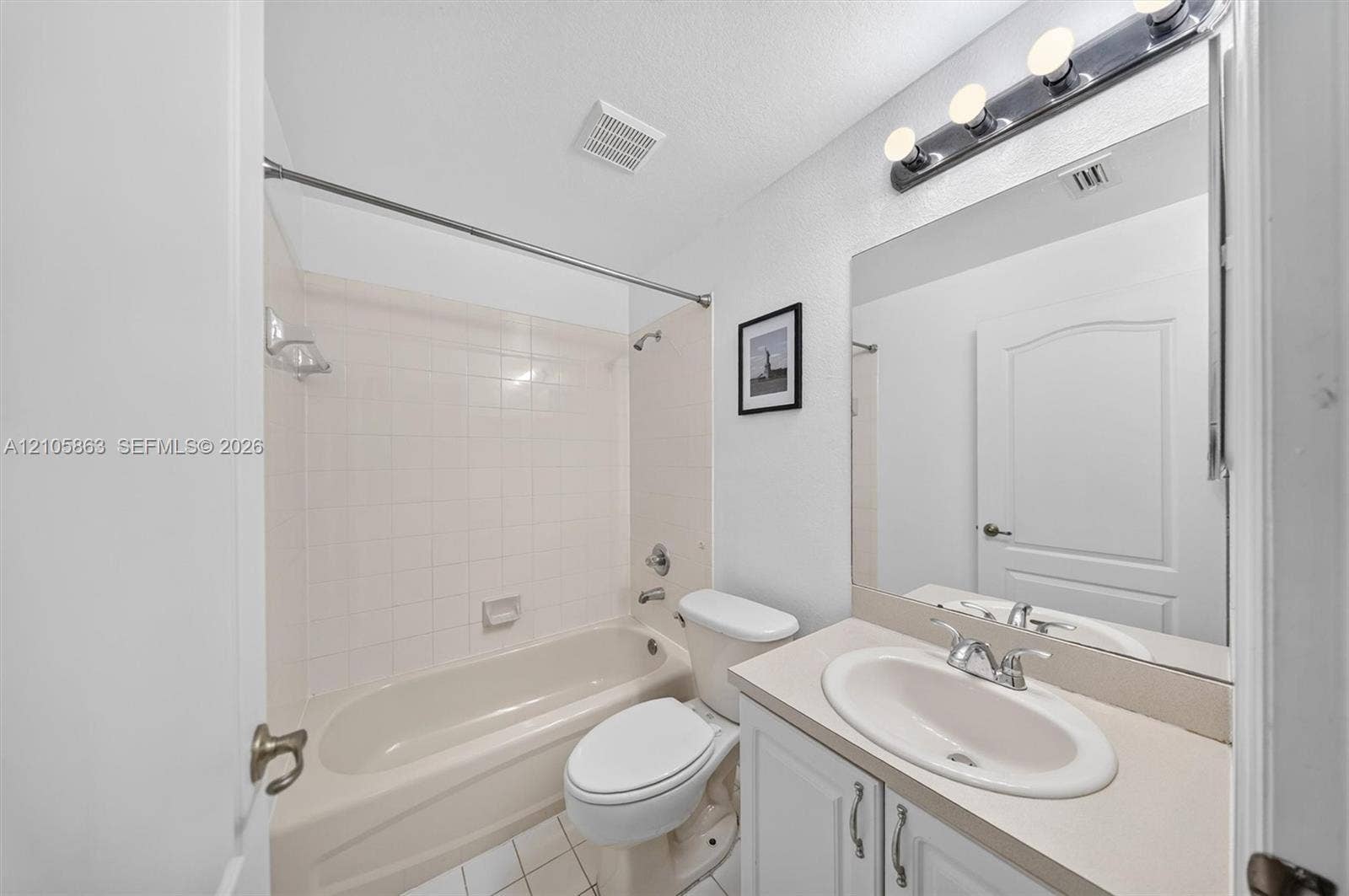 8846 W Flagler Street, #5, Miami, FL 33174 Full bathroom featuring a white vanity with a neutral solid-surface countertop, integrated oval sink, chrome dual-handle faucet, and an oversized wall mirror with a multi-bulb light fixture