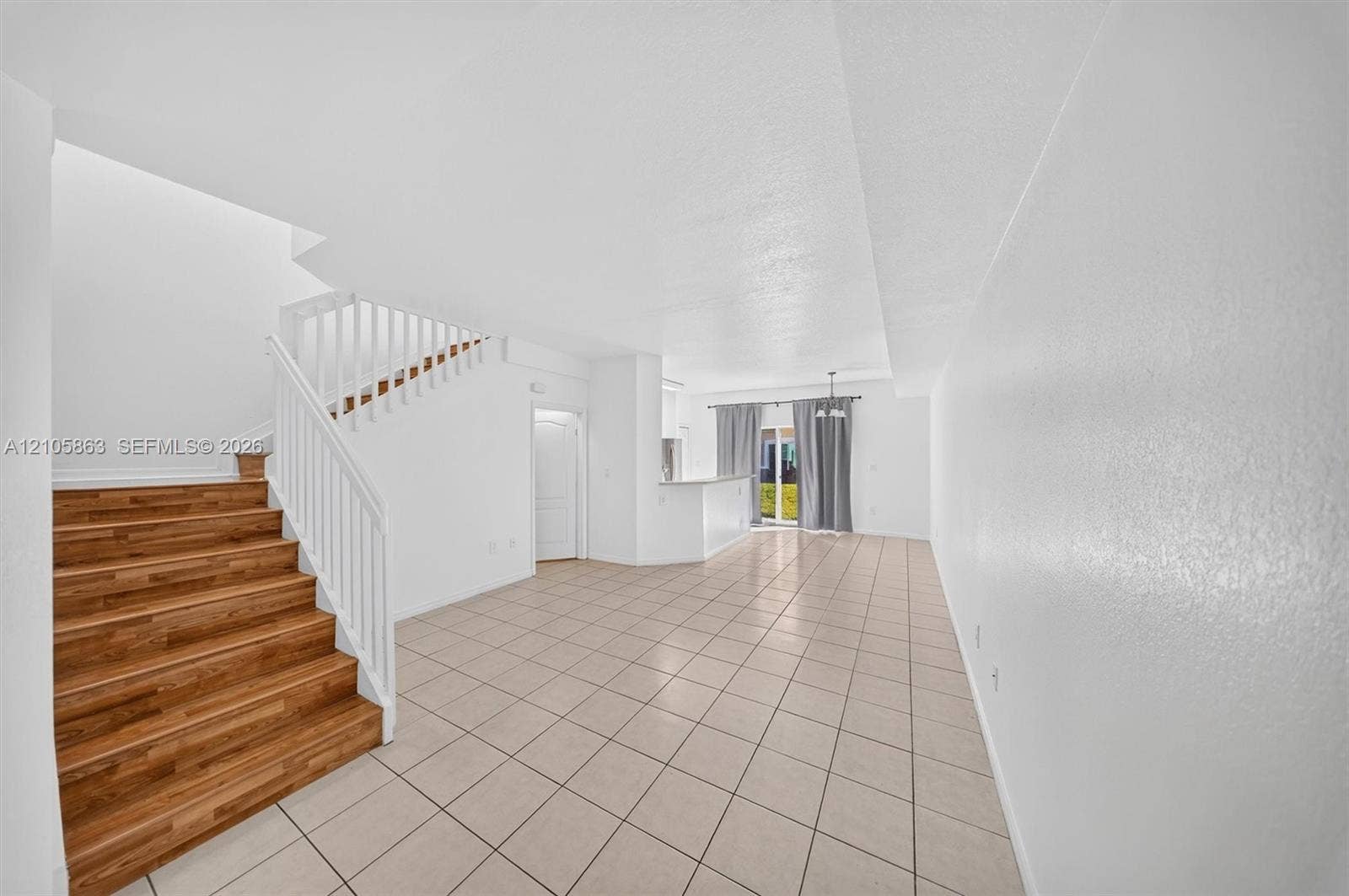 8846 W Flagler Street, #5, Miami, FL 33174 Open floor plan featuring wood-finish stairs, white balustrades, large-format tile flooring, and a breakfast bar