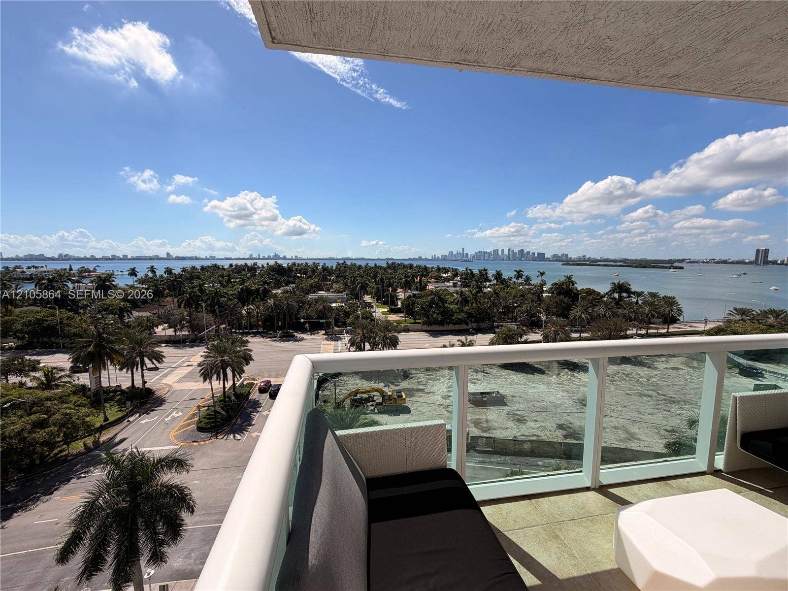 Covered balcony with a glass and metal railing, concrete flooring, and an expansive skyline and water panorama