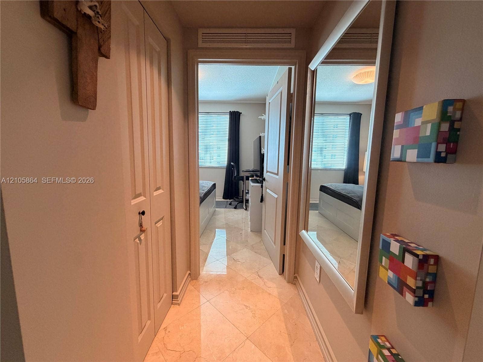 Polished stone tile flooring, bi-fold closet doors, and a large wall-mounted rectangular mirror