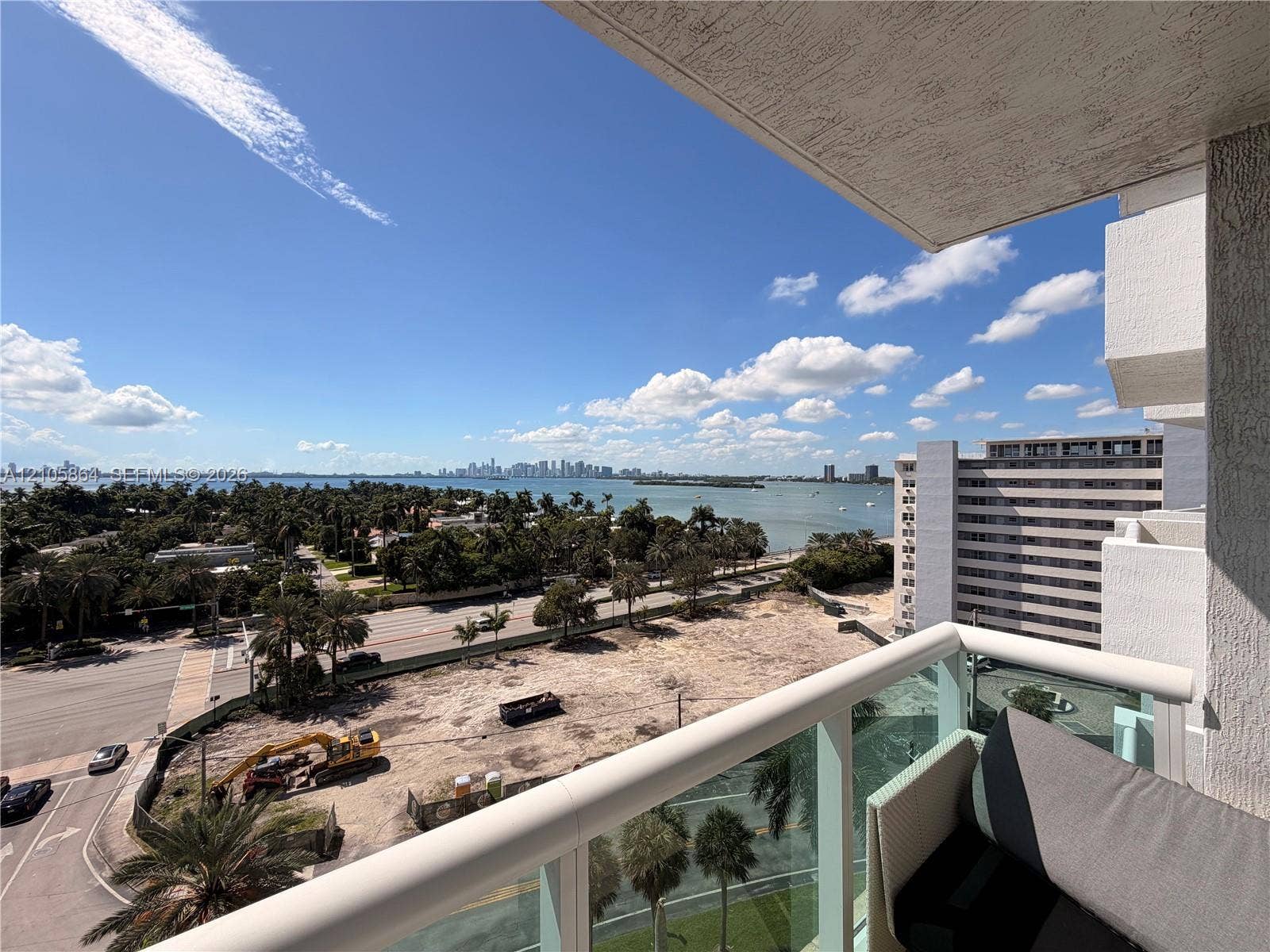 Private balcony with a glass and metal railing, featuring panoramic coastal and city skyline scenery