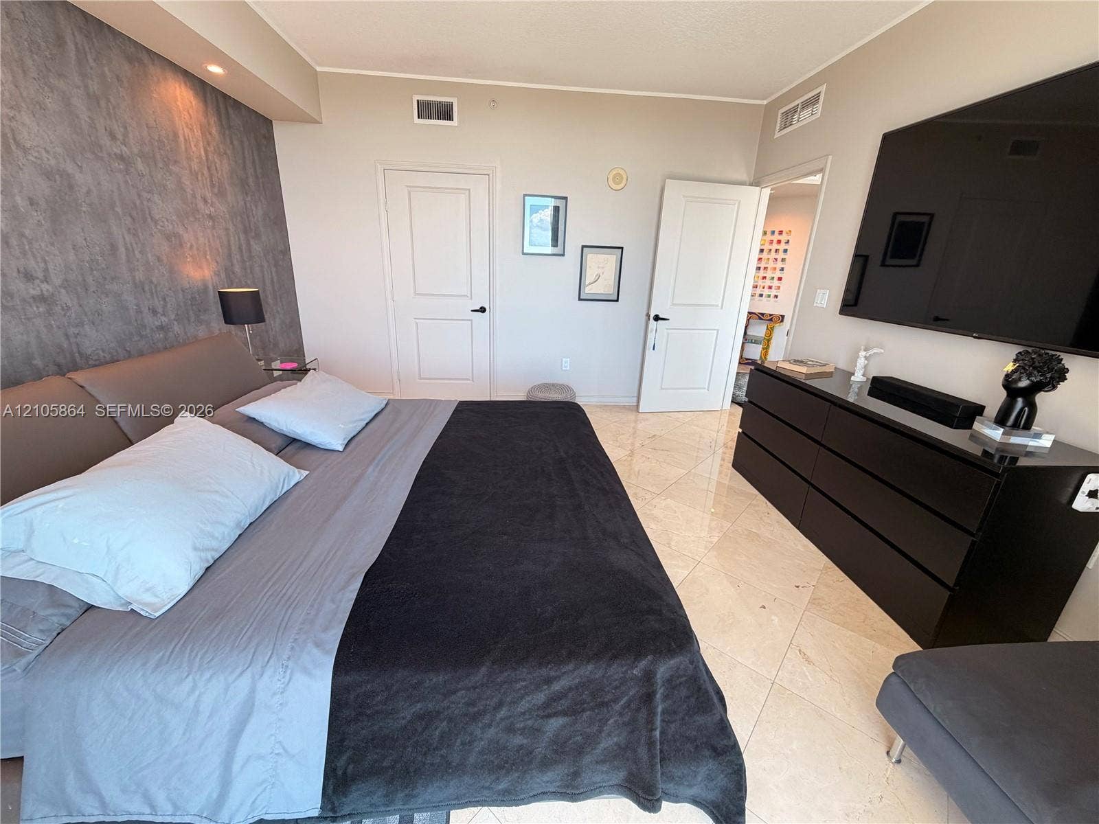Textured grey feature wall, polished stone-finish flooring, and two-panel interior doors with matte black hardware