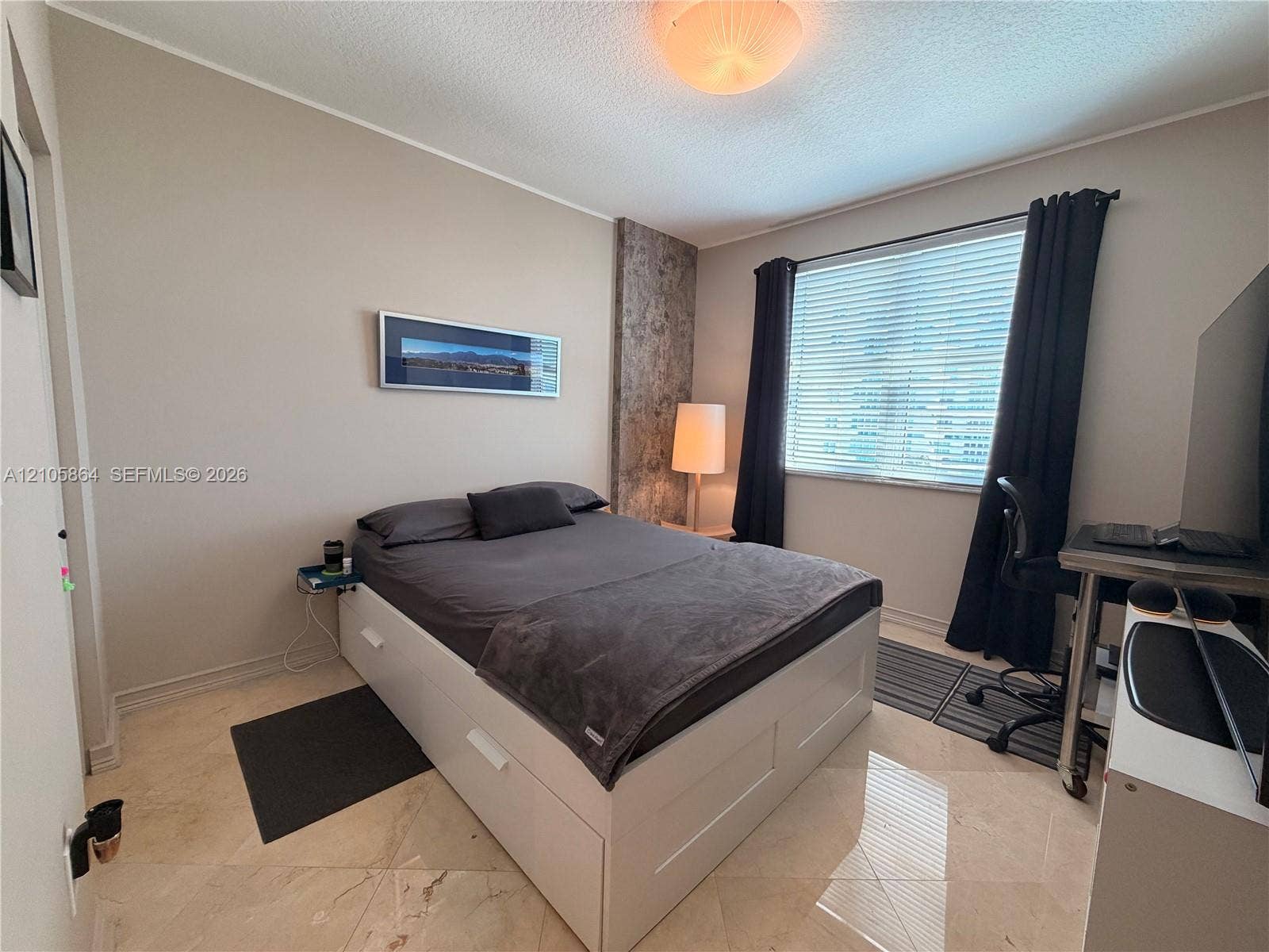 Polished stone flooring, textured wall accent panel, and window featuring horizontal blinds