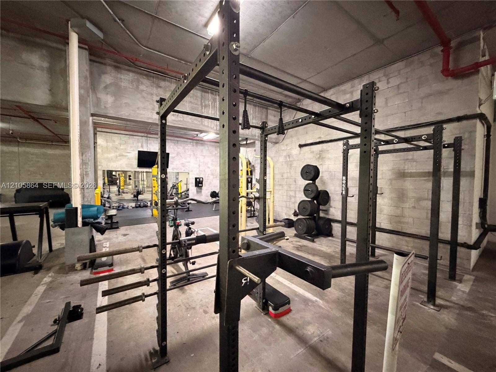 Industrial-style fitness space featuring concrete block walls, exposed structural elements, and concrete flooring