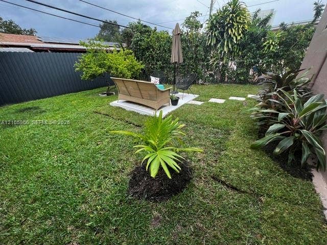 11241 SW 7th Terrace, Sweetwater, FL 33174 1/1 's Backyard featuring a grass lawn, paved square patio area, perimeter fencing, and established landscape plantings
