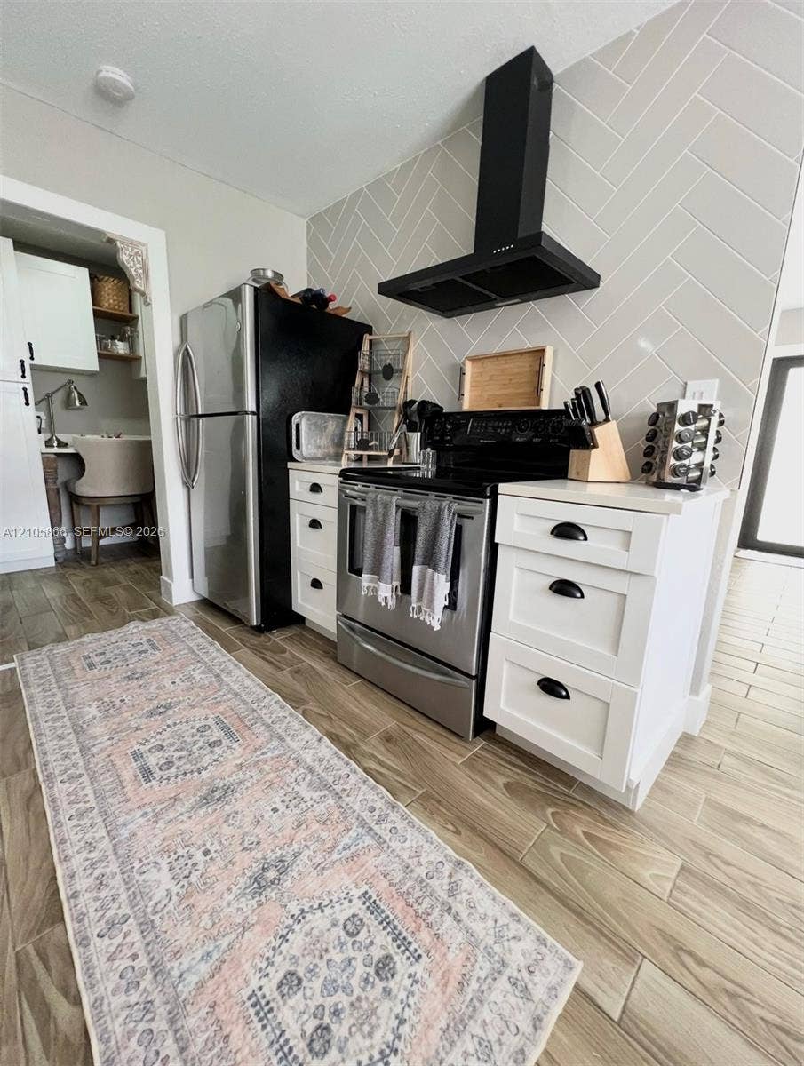 11241 SW 7th Terrace, Sweetwater, FL 33174 Main House Kitchen featuring white shaker-style cabinetry with matte black hardware, herringbone-patterned wall tile, stainless steel appliances, and wood-finish flooring