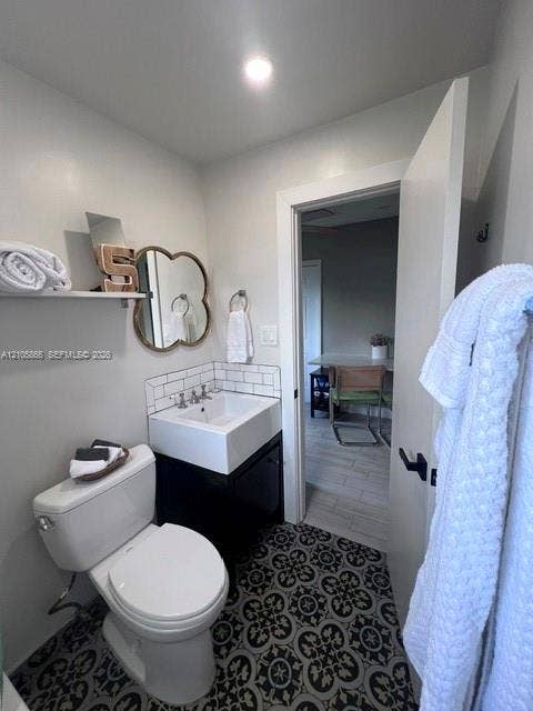 11241 SW 7th Terrace, Sweetwater, FL 33174 Bathroom featuring patterned floor tile, square vessel sink with wall-mounted faucet, subway tile backsplash, and wall-mounted storage shelving
